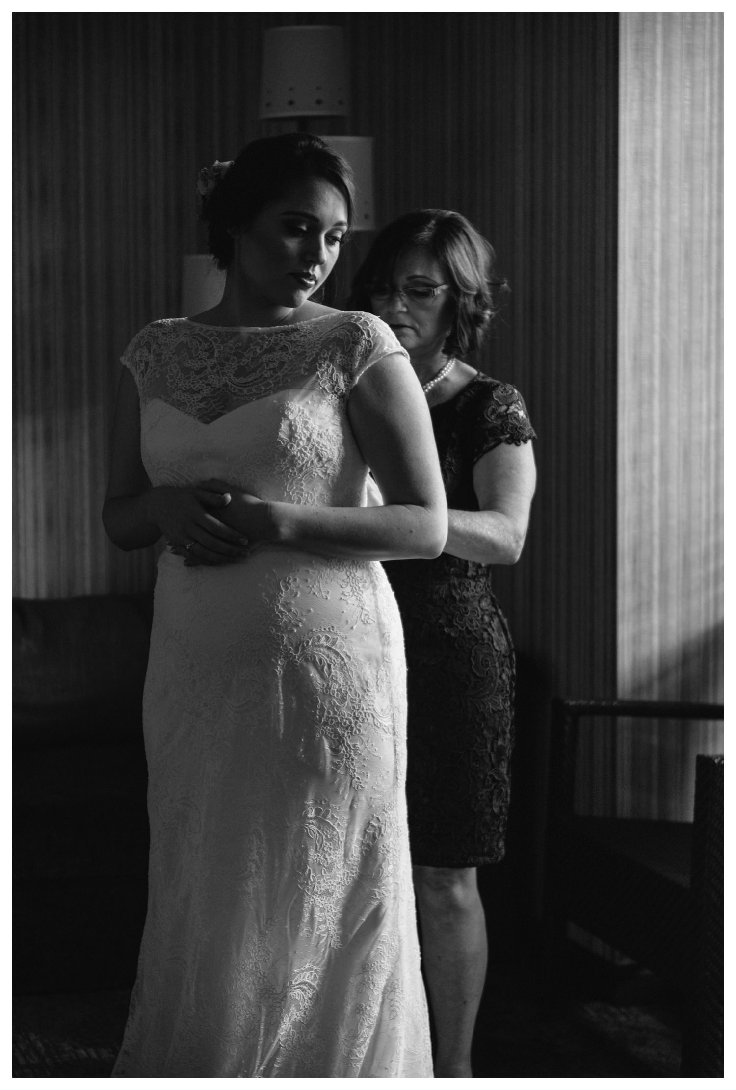 a mother helps her daughter into her wedding dress