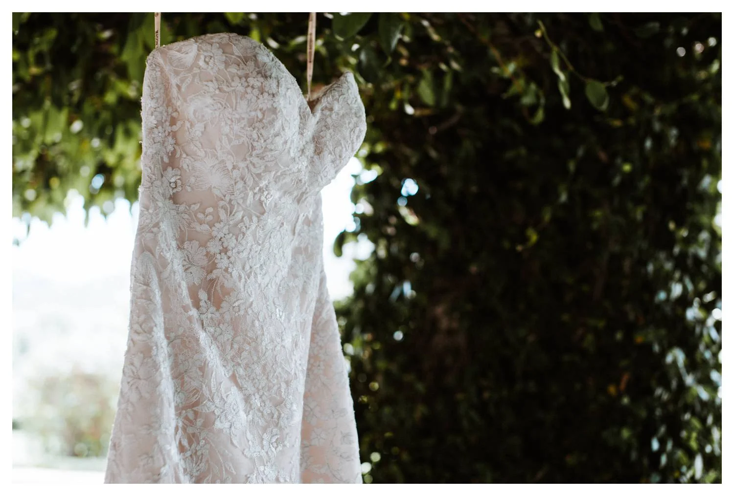 Details of a wedding dress against a green ivy wall