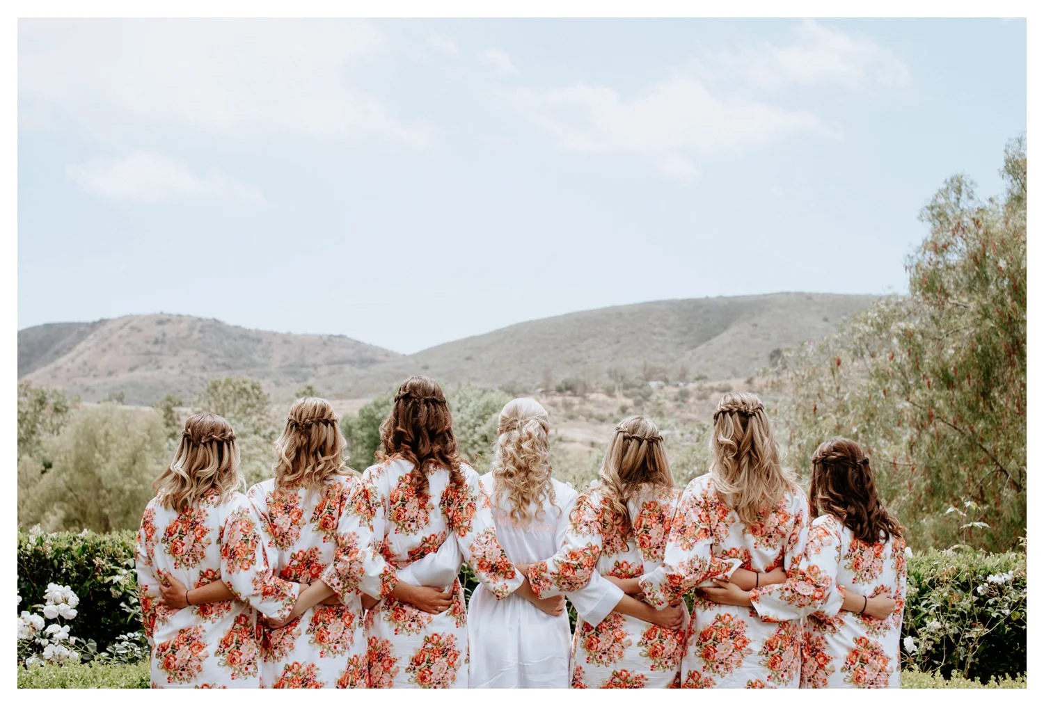 A group of bridesmaids huddle in their trendy silk robes