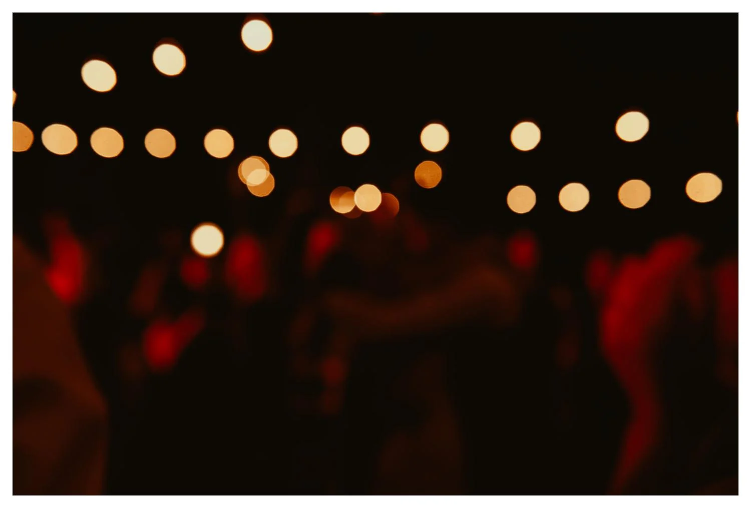 The twinkle of bokeh balls looms over a wedding dance floor.