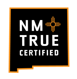 NM True Certified logo with black background, white text, orange outline, and a New Mexico Zia symbol.