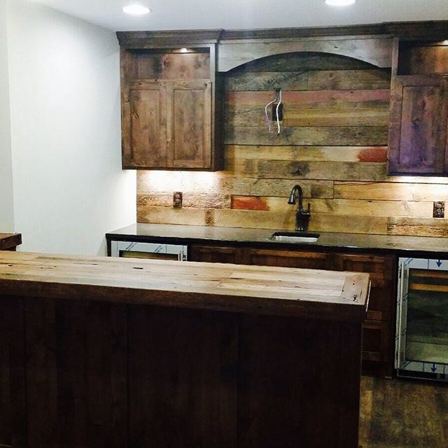 Basement bar with reclaimed wood bar top and accent wall.