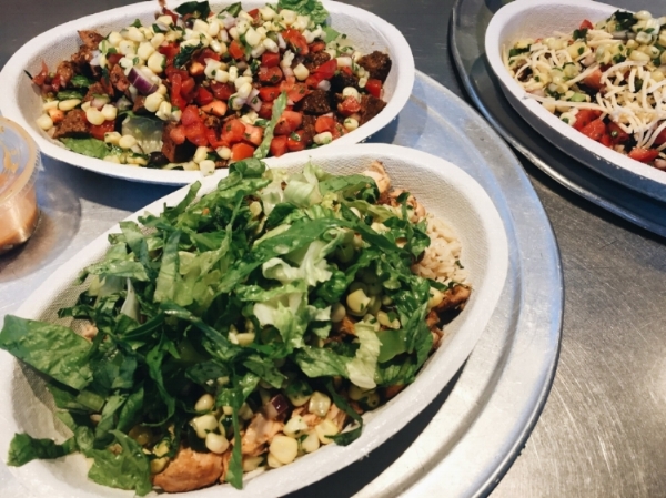 Pictured here: Burrito bowl with rice, chicken, black beans, lettuce, corn, tomato, and guac. 