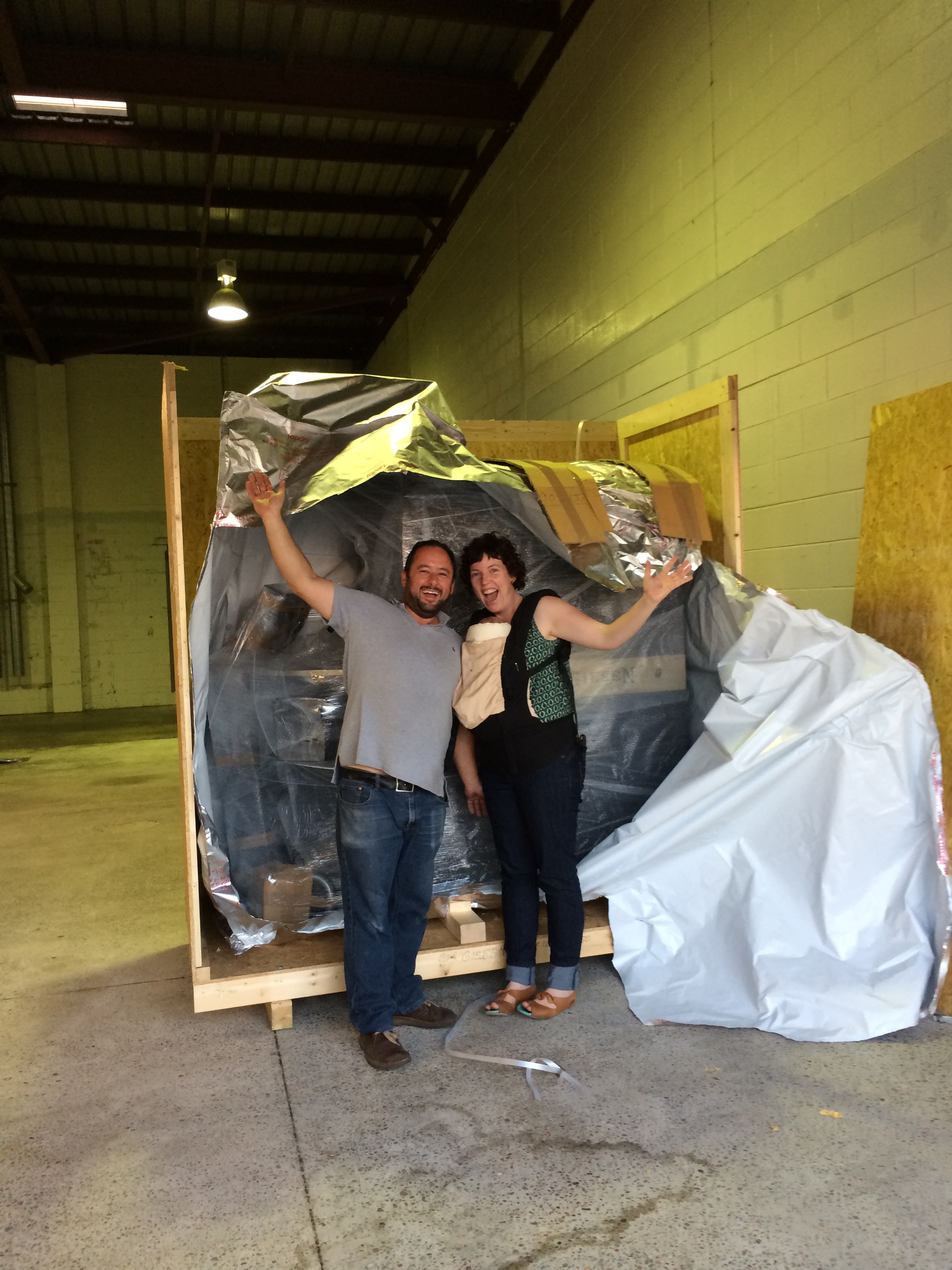Katie wearing tiny baby Artie as they unpack the second roaster.