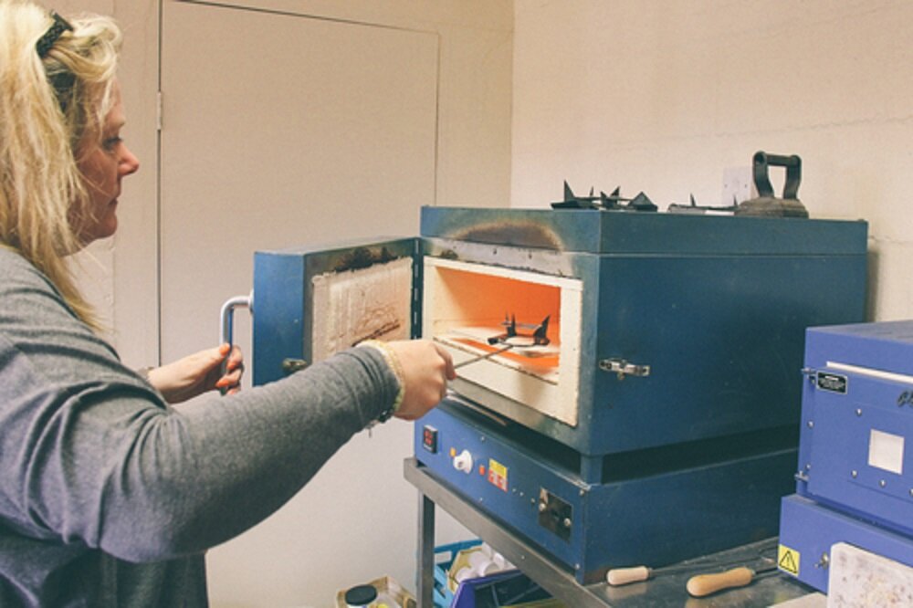Teresa putting a picture into the kiln to fire.