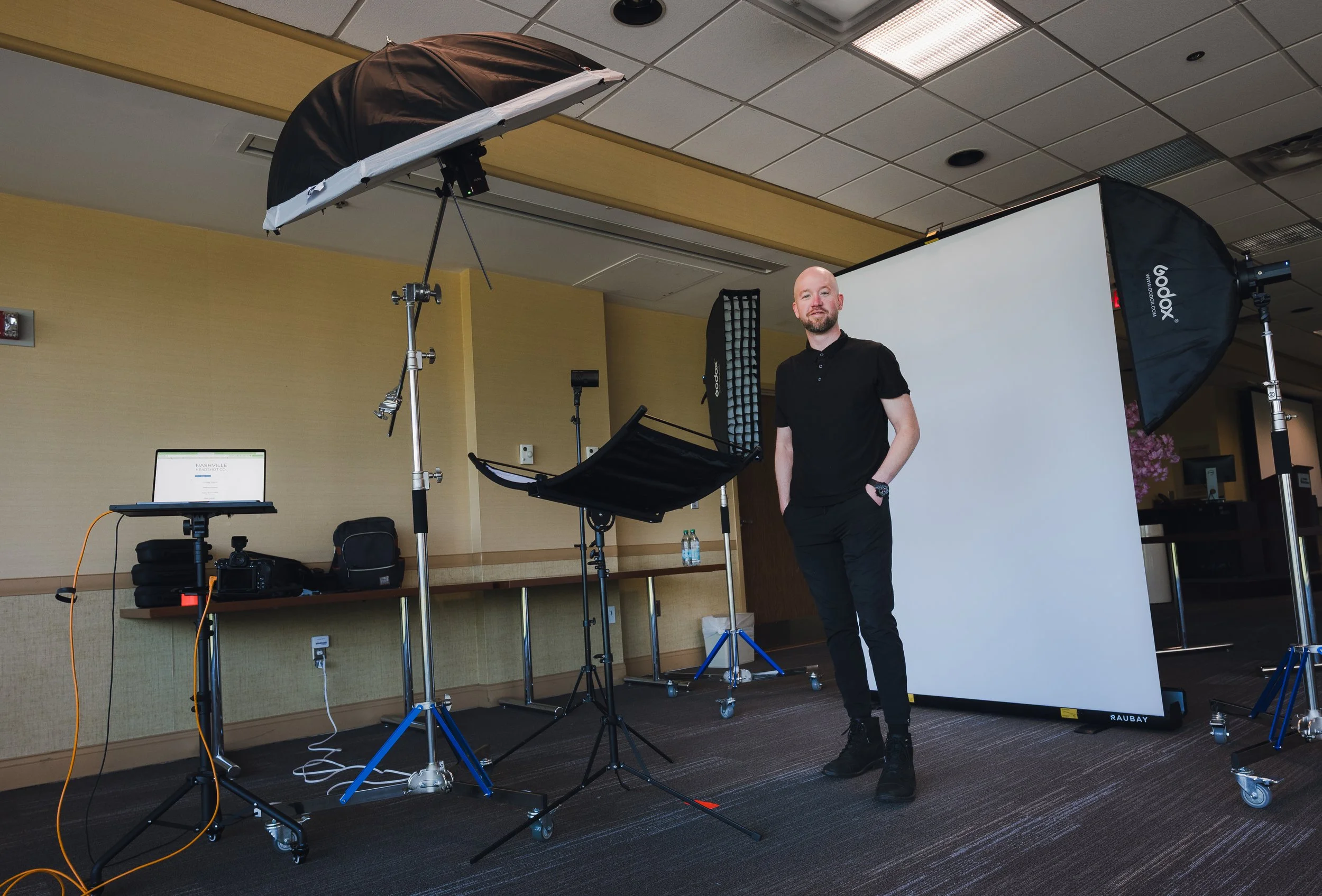 bald man standing in mobile photo studio setup for headshots