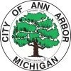 Logo is the City Seal of Ann Arbor. Inside a circle border is a green tree with a brown trunk. Ringing around the tree is text reading, "City of Ann Arbor Michigan."