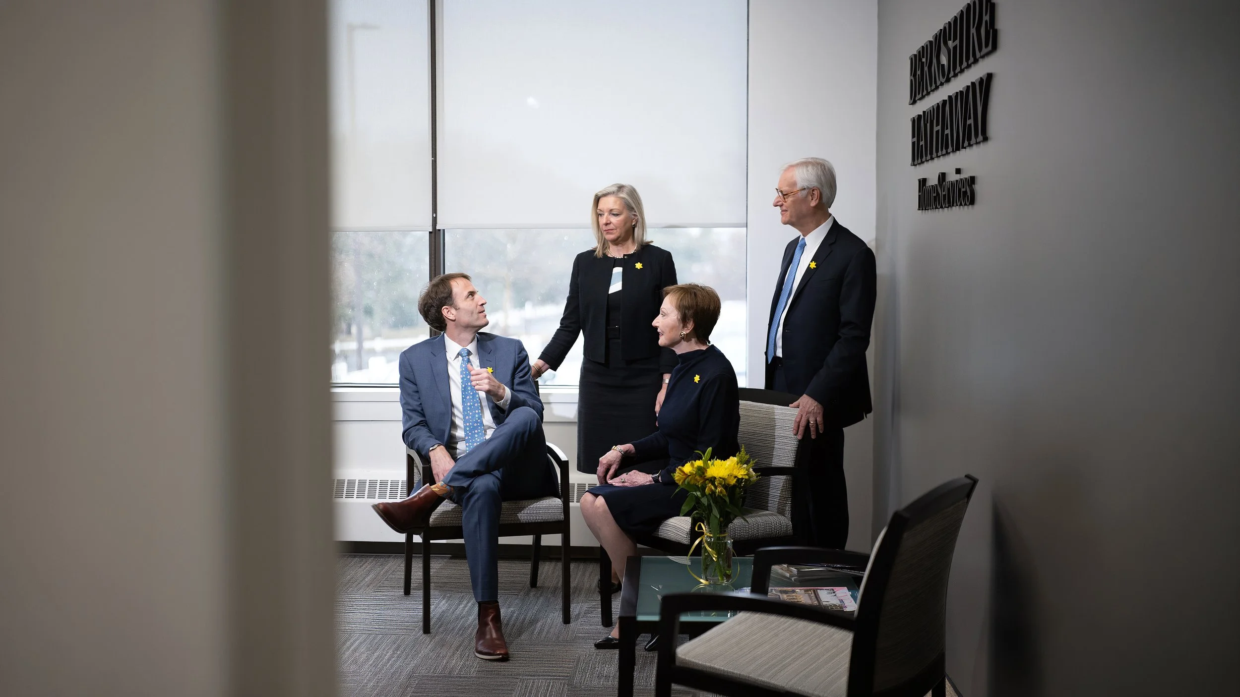 Four Berkshire Hathaway HomeServices professionals gathered in conversation within a naturally lit office, photographed by Charles Maring.