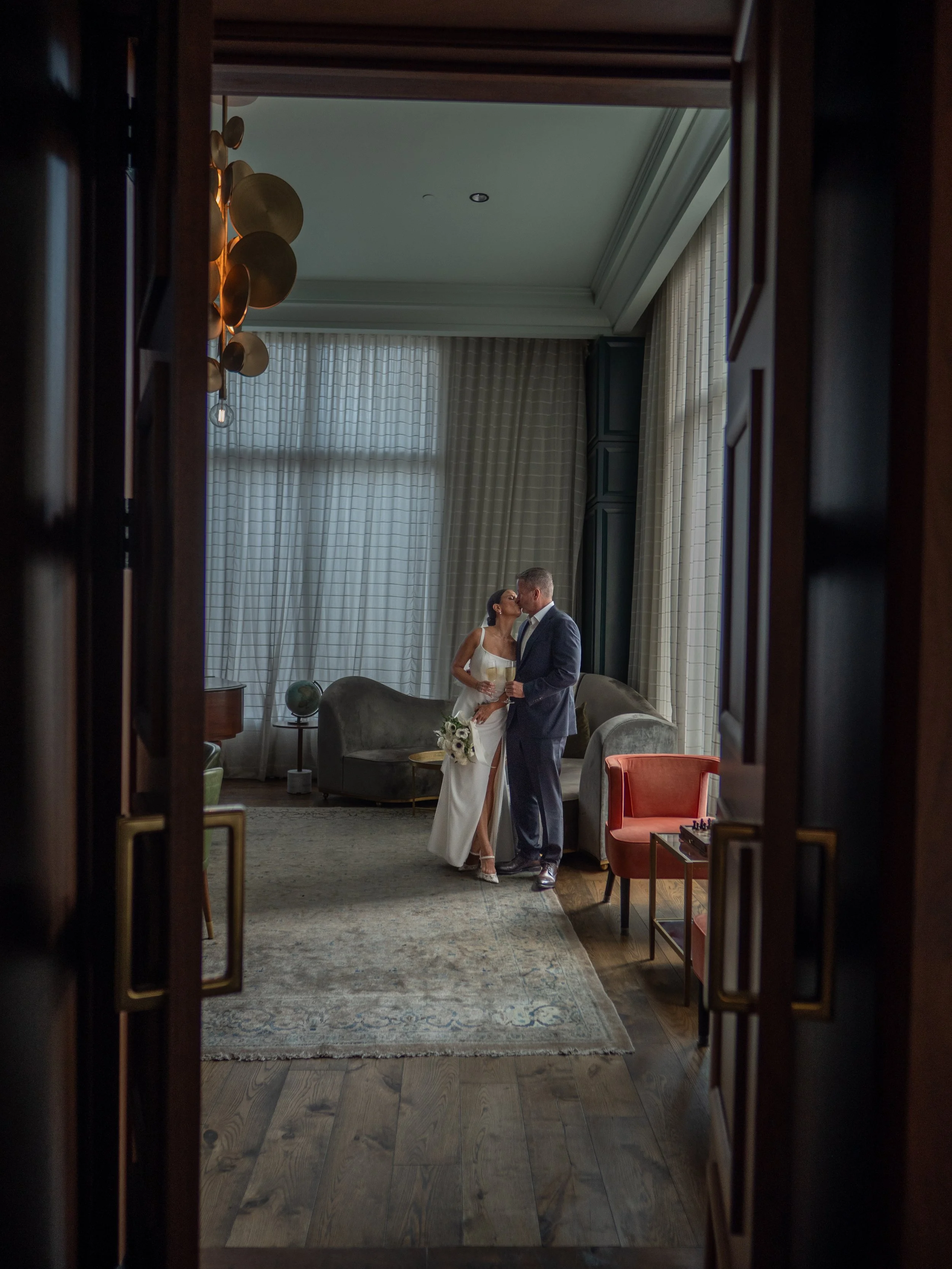 Kate and Ryan embracing during their first look, photographed through the doorway of the Perry Lane Hotel library