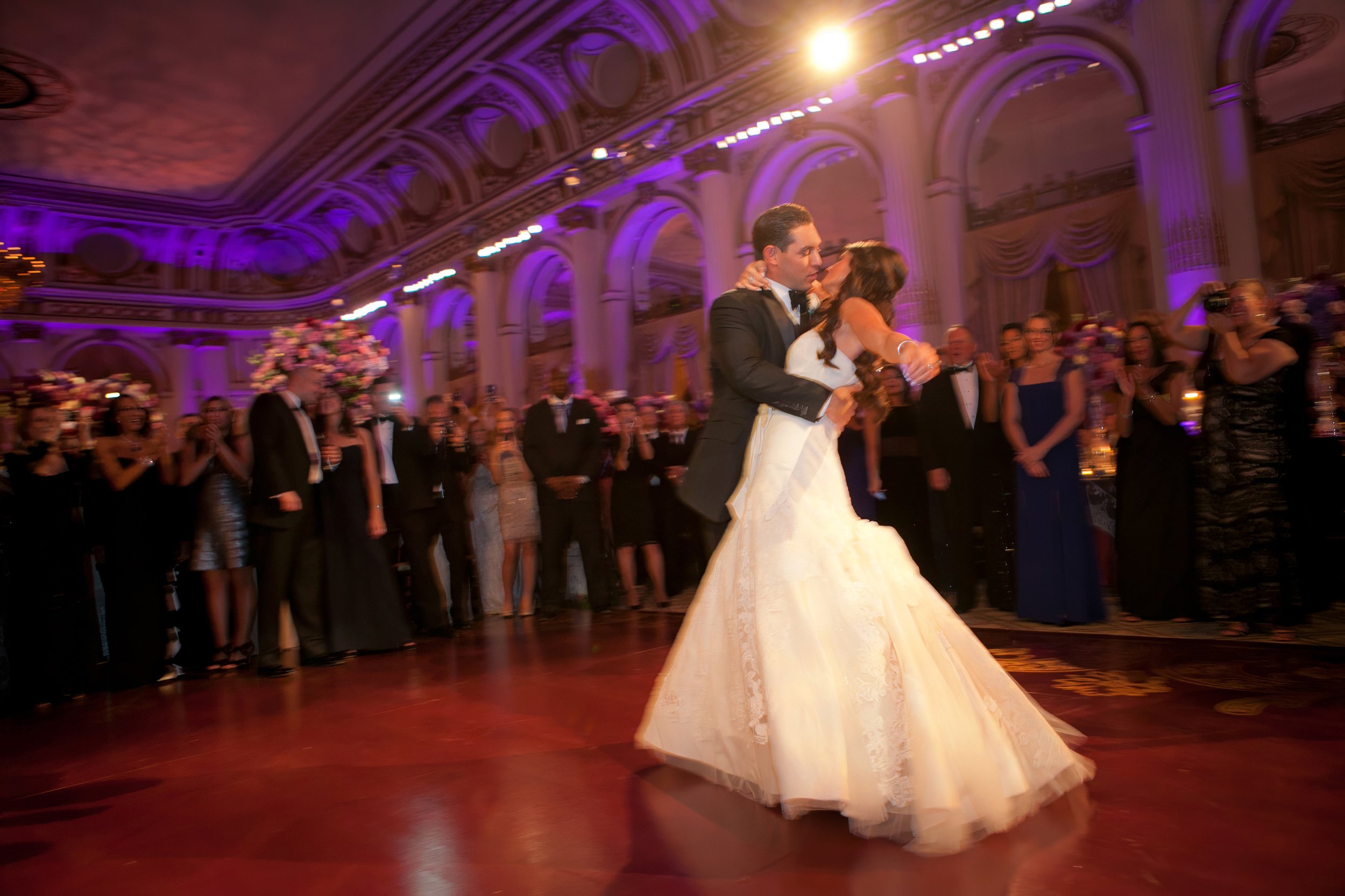 Bride and groom share their first dance beneath purple lighting in The Plaza Hotel ballroom in New York City.