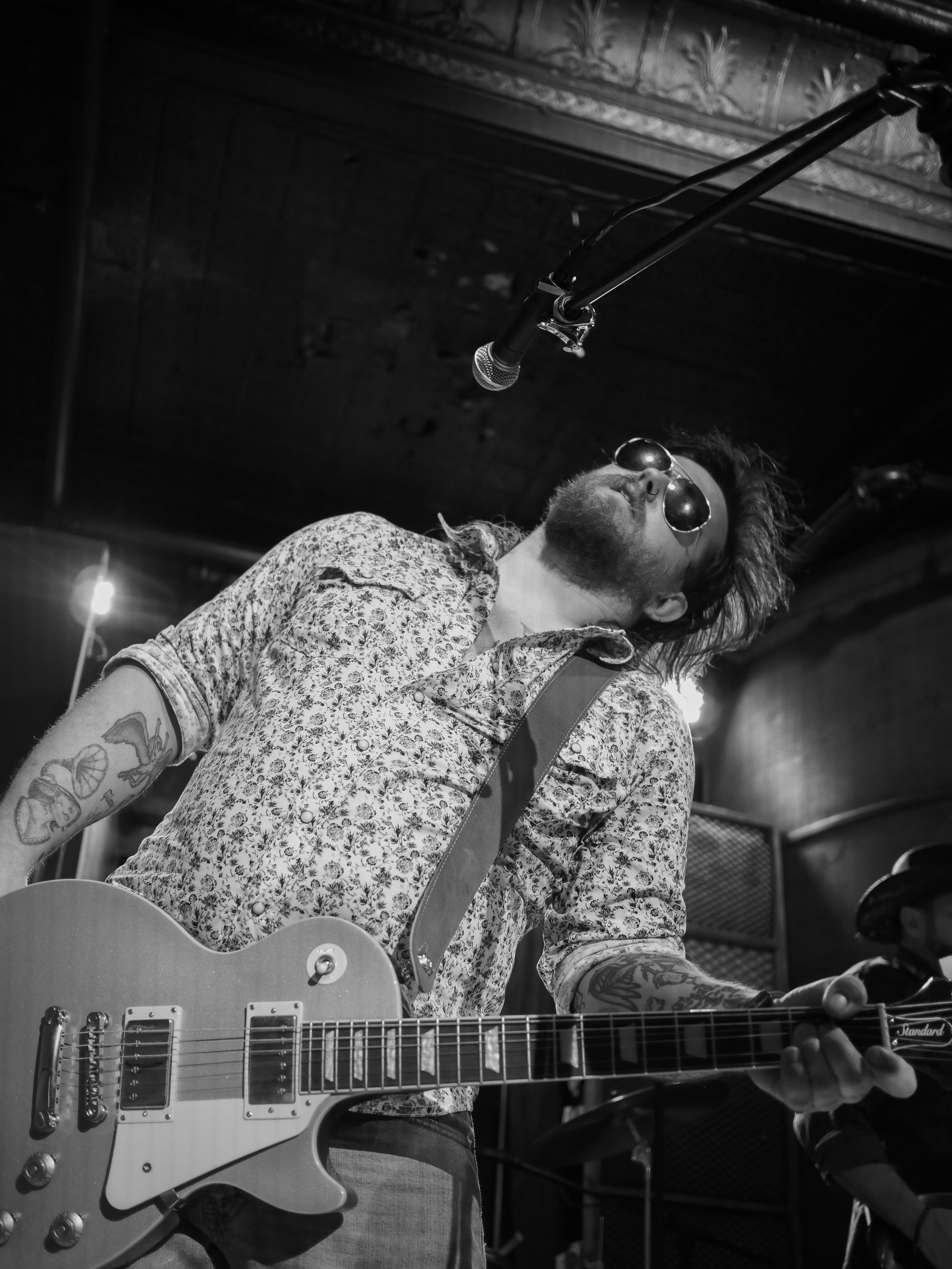 Darrell Anthony leaning back with an electric guitar during a black and white live performance.