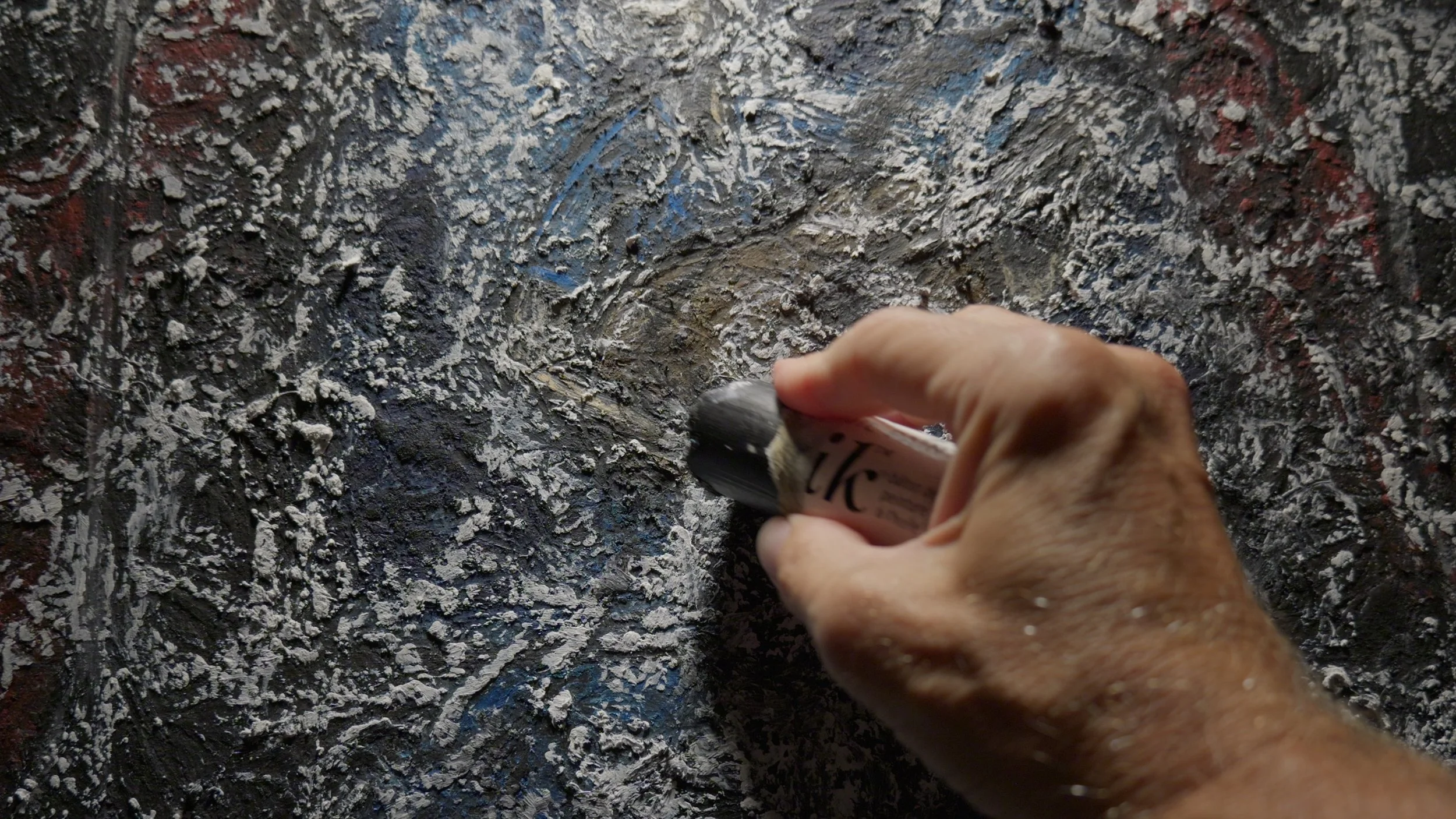 Charles Maring applies a Shiva Oilstick to the heavily textured surface of an abstract oil painting.