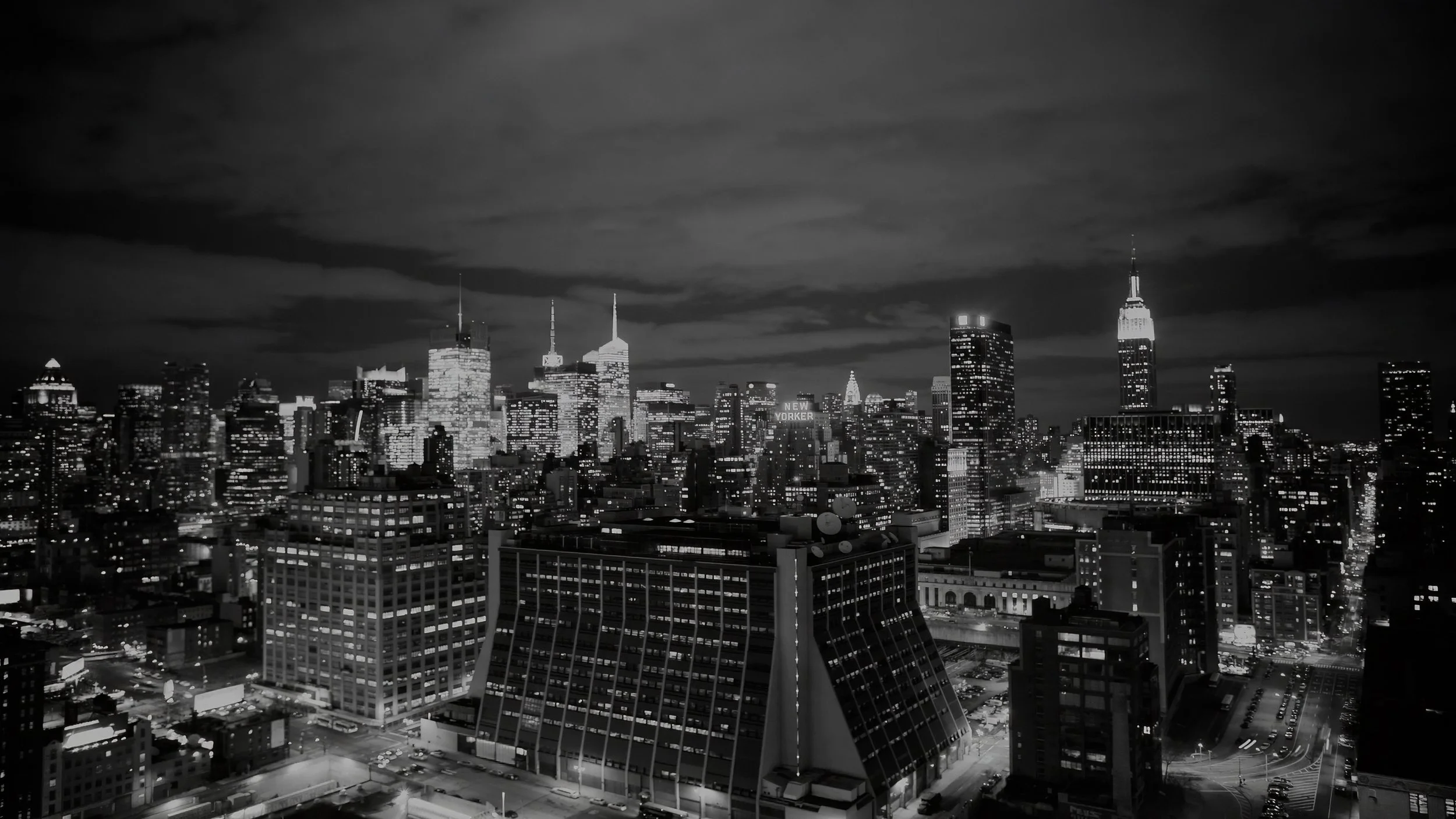 New York City skyline and Empire State Building photographed at night in black and white.