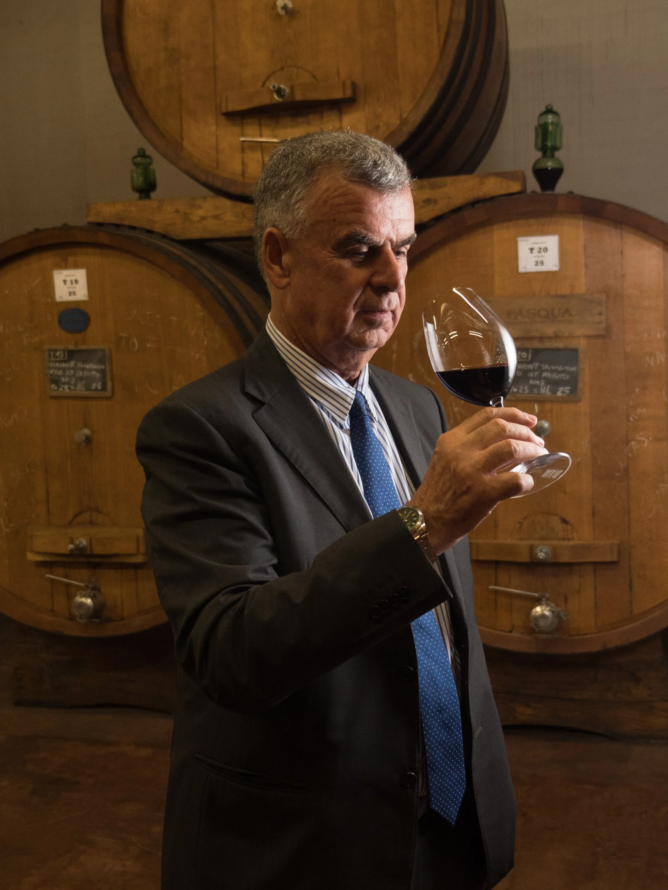 Environmental editorial portrait in a working wine cellar, using the barrels, glass and available atmosphere to tell a larger story about the subject.