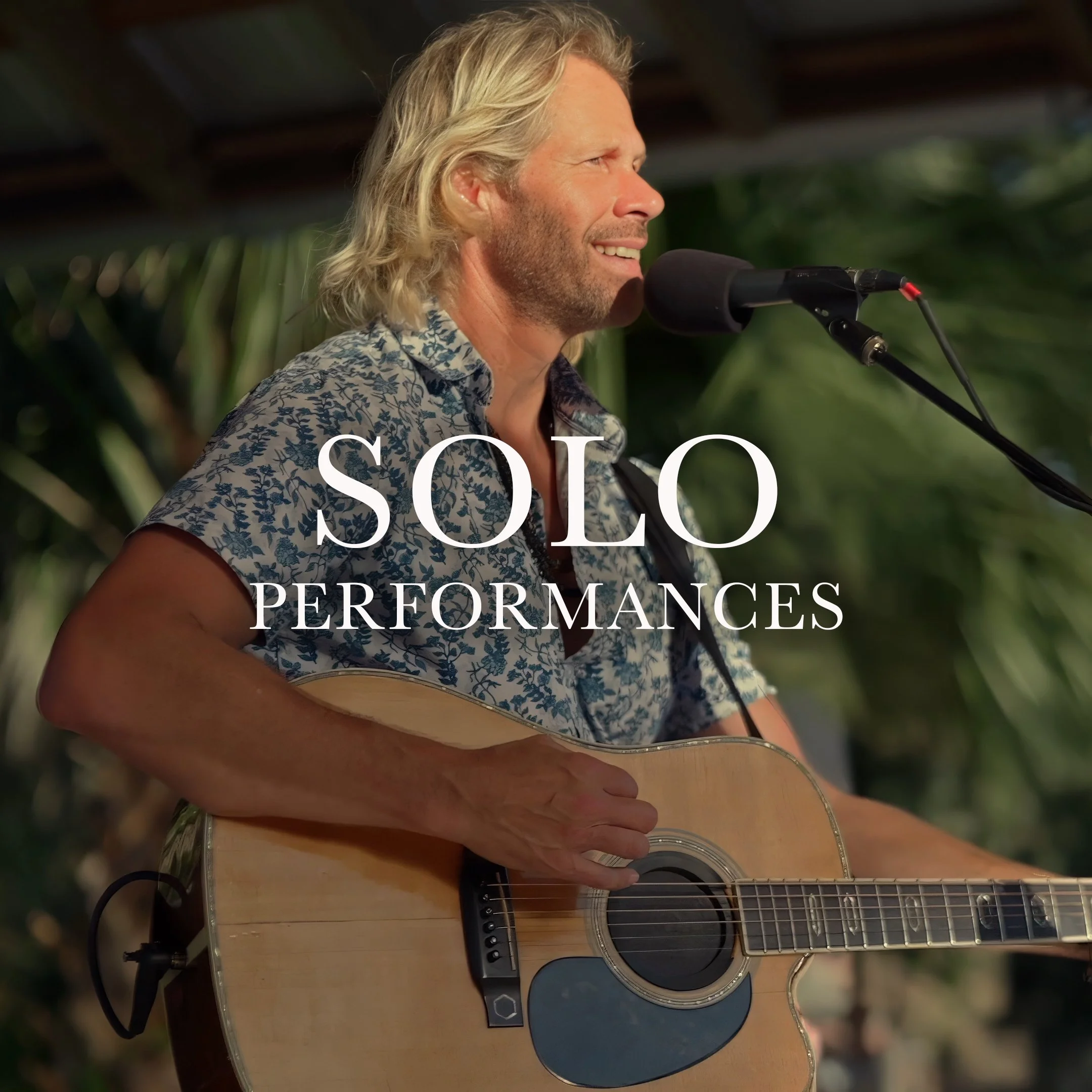 Charles Maring smiling while performing a solo acoustic guitar performance outdoors in bright sunlight