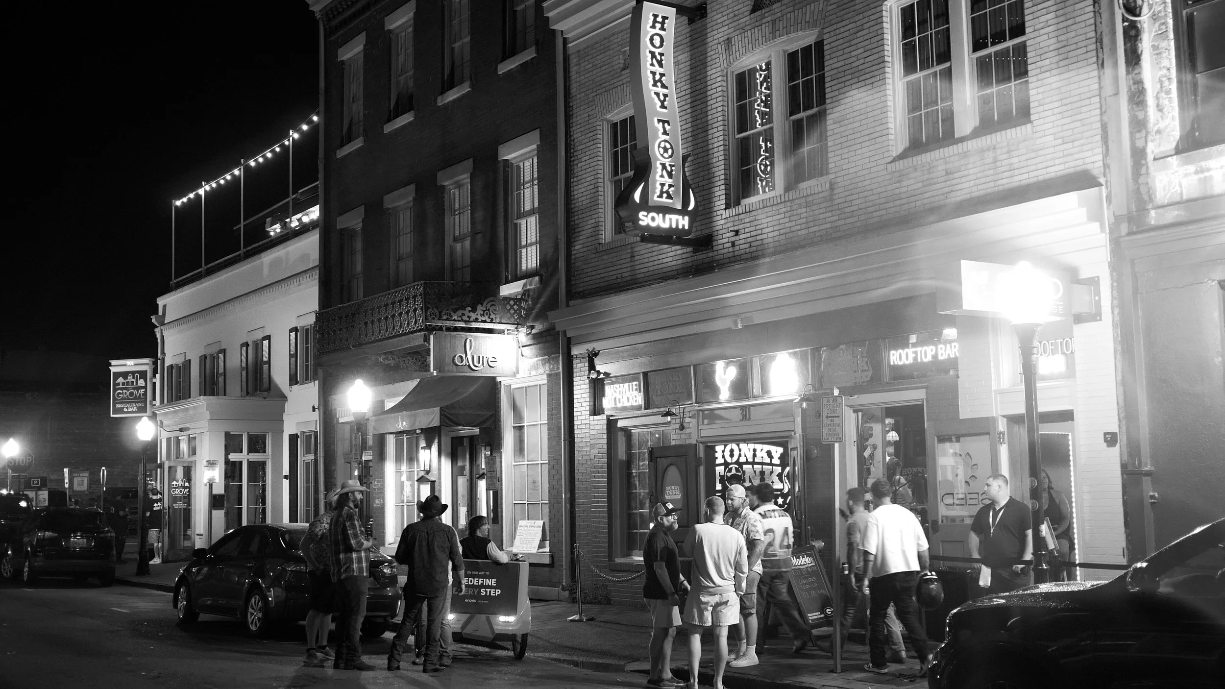 Nighttime exterior of Honky Tonk South with people gathered along West Congress Street in downtown Savannah.
