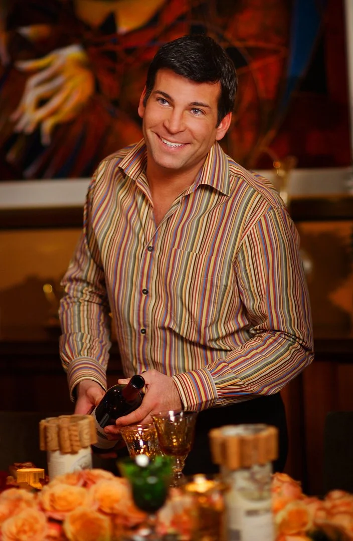 David Tutera photographed in a candid moment while pouring wine at an elegantly styled table.