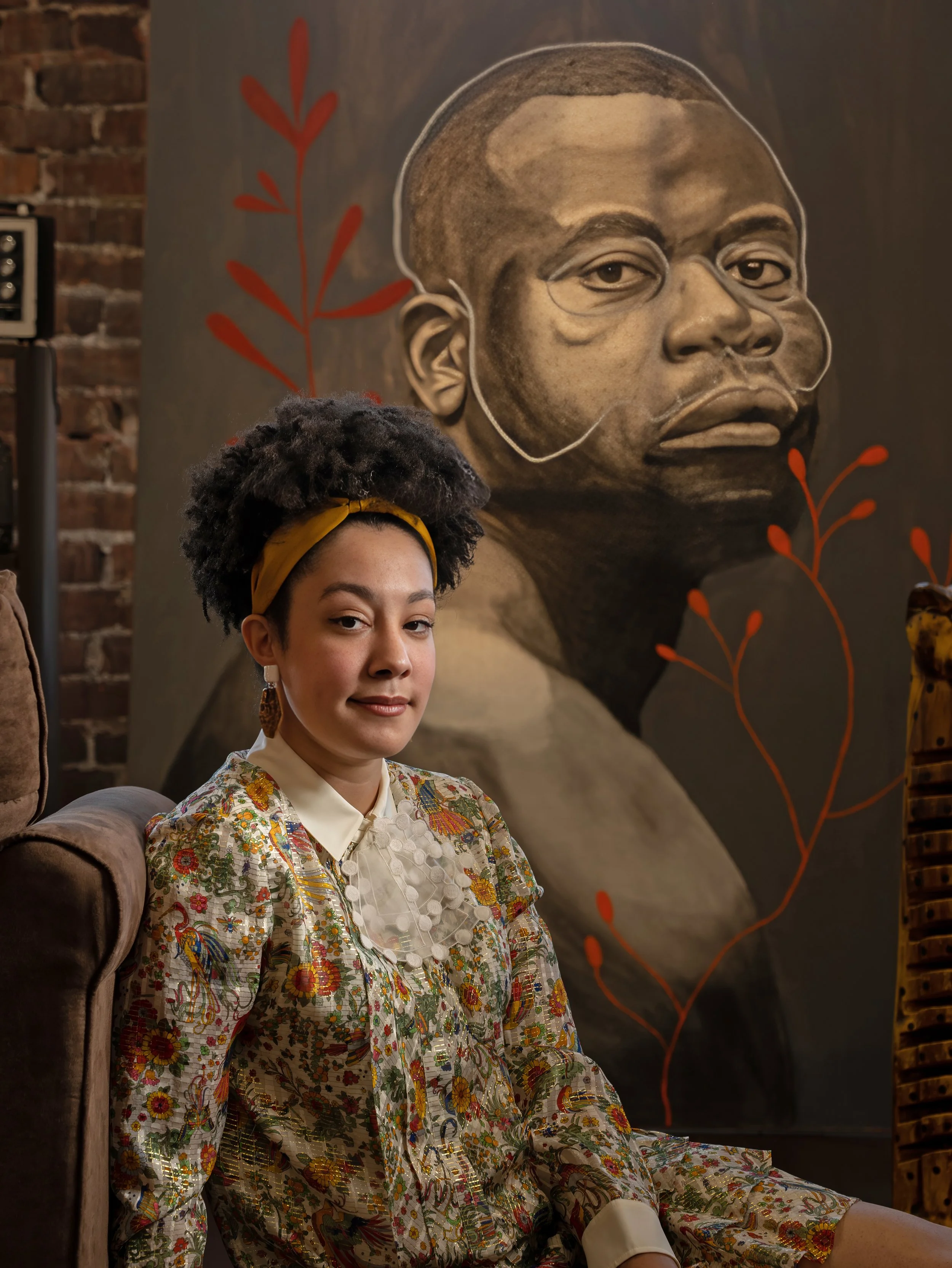 Savannah artist Tafy Laplanche laughing in an armchair surrounded by paintings and artwork inside her creative studio, photographed by Charles Maring.