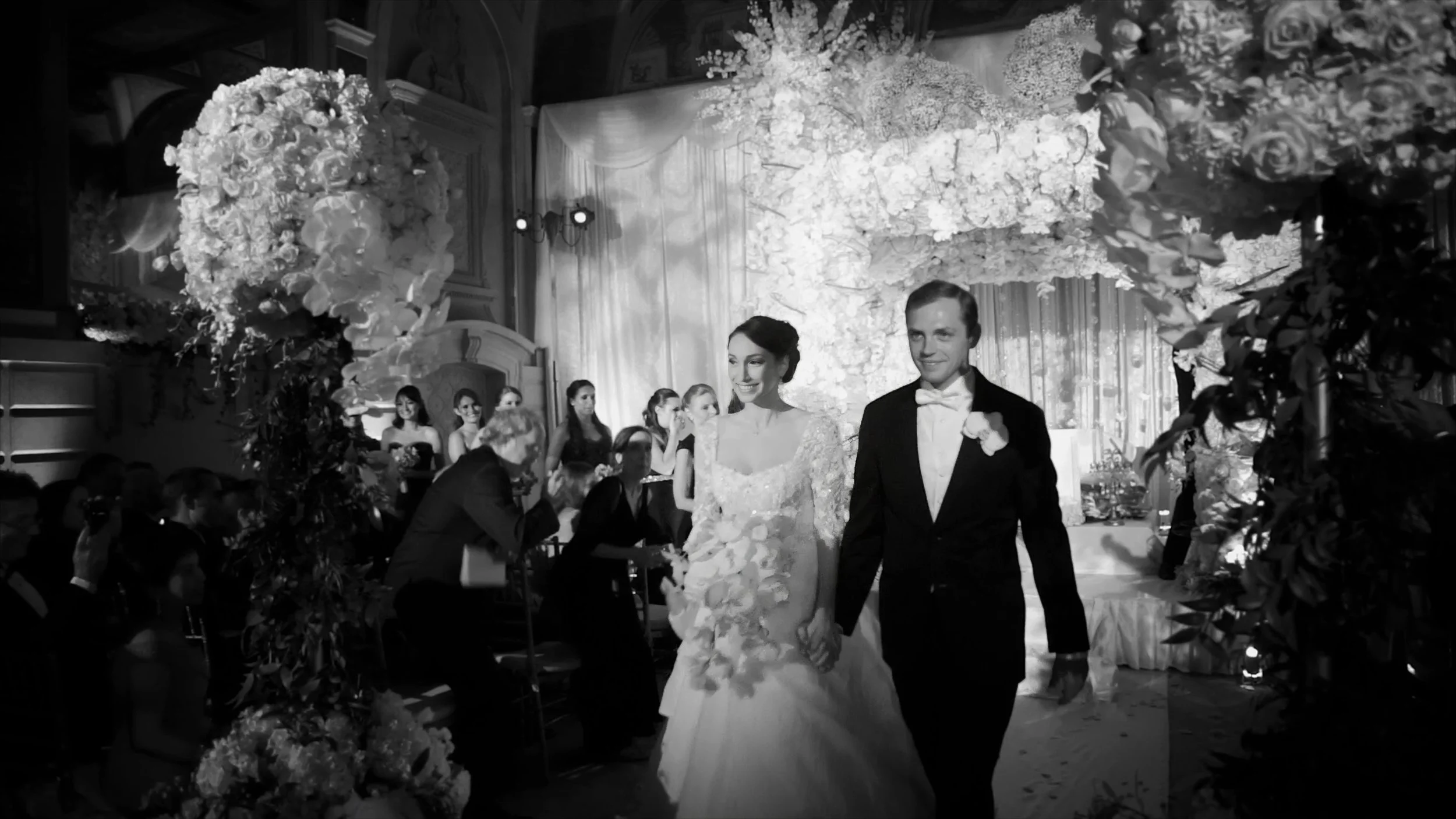 Newly married couple walking through the floral ceremony setting at The Plaza Hotel in New York.