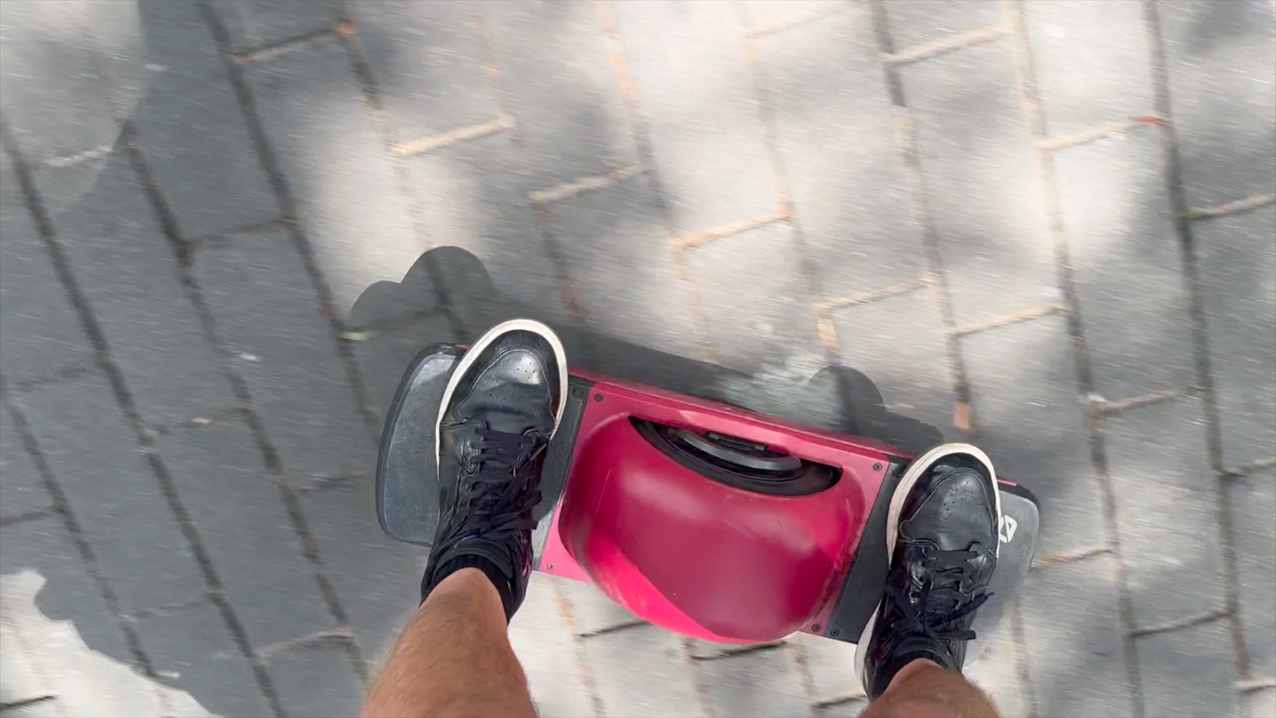 A red Onewheel moves across a brick street in downtown Savannah beneath Charles Maring’s feet.