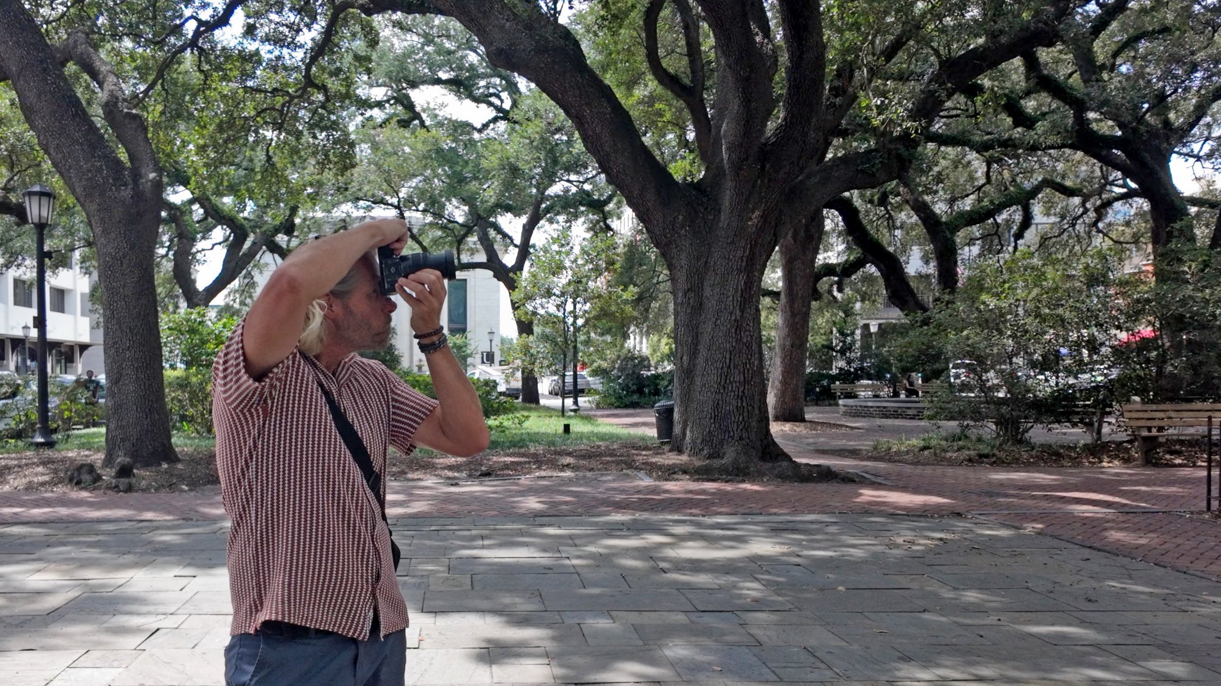 Charles Maring photographs historical details beneath the live oaks in Johnson Square in downtown Savannah.