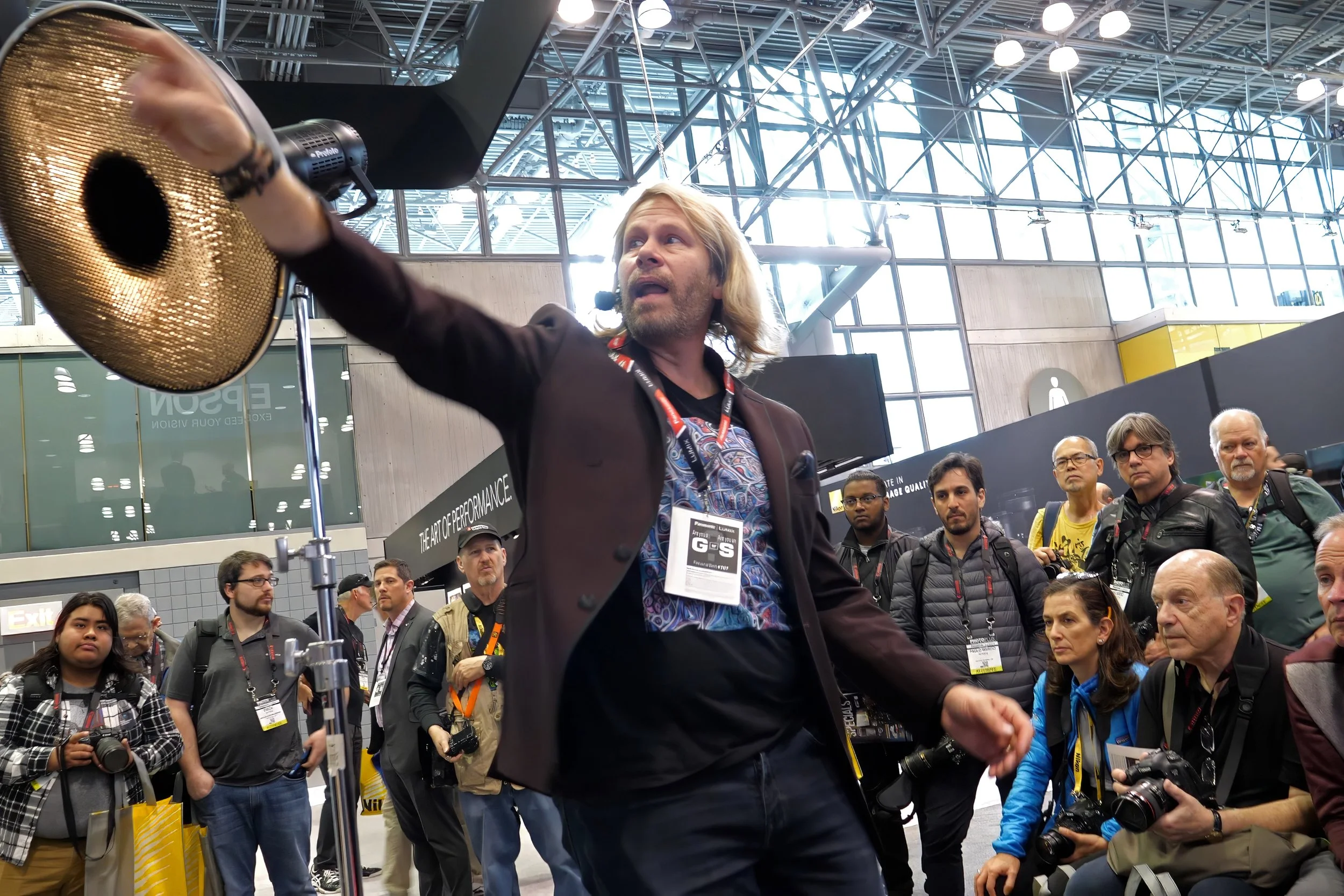 Charles Maring speaks on a conference stage as an image coach, teaching lighting, photography, and visual brand presentation to an audience.
