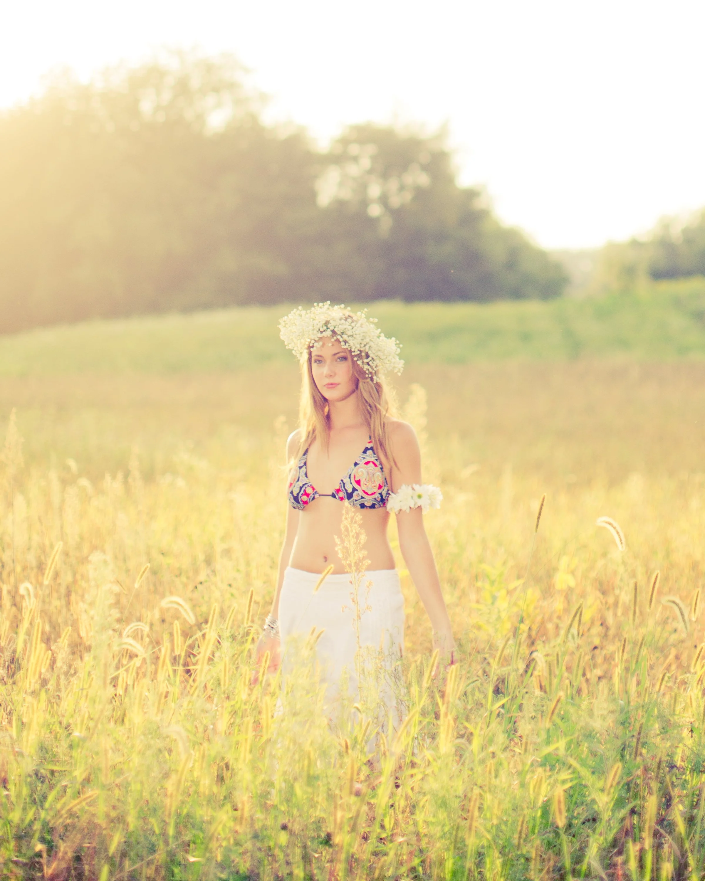 Fashion portrait created in a sunlit field, allowing backlight, atmosphere and the landscape to become part of the image.