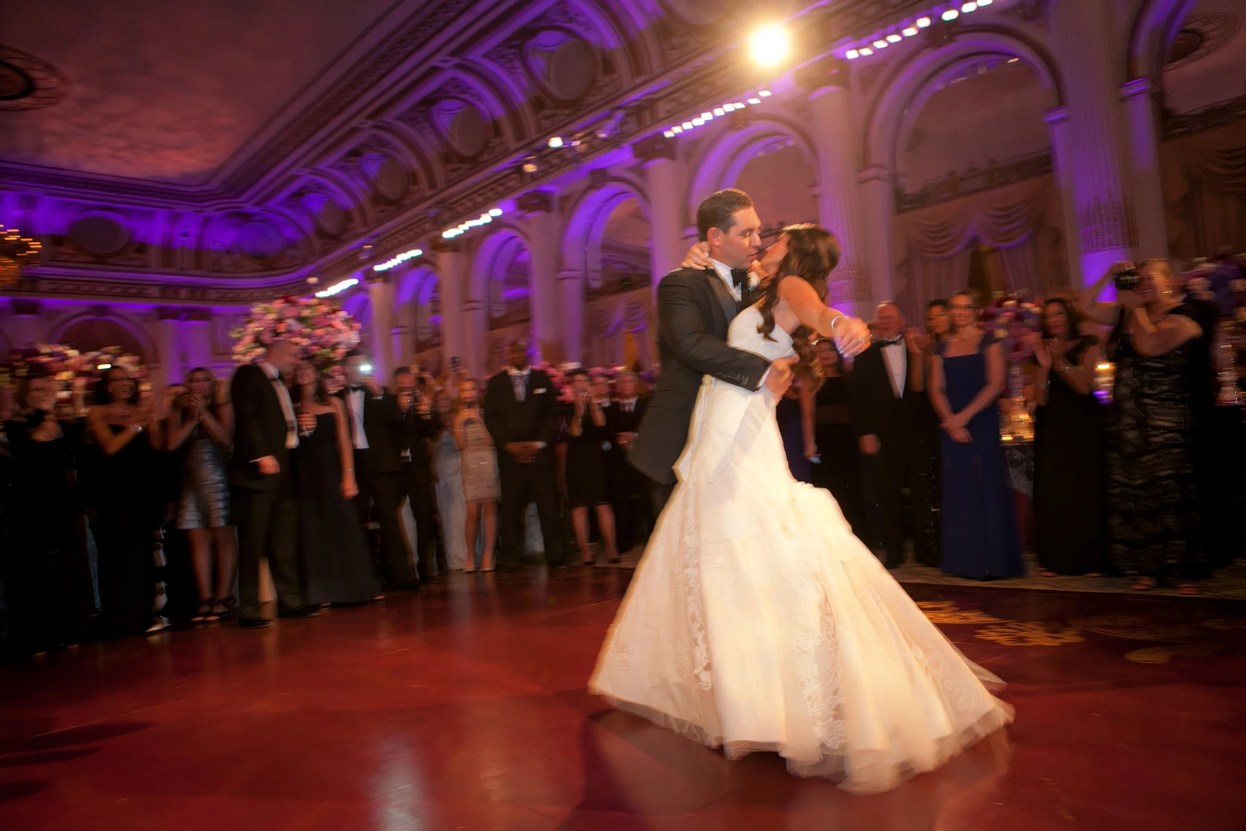 A groom prepares to dip his bride for a kiss during their first dance in the Grand Ballroom at The Plaza Hotel in New York City, photographed by Charles Maring.