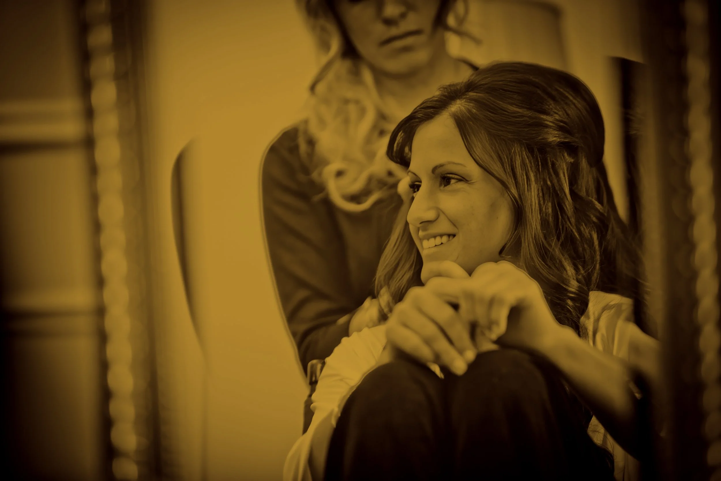 Split toned candid portrait of a smiling bride seated during wedding preparations at The Plaza Hotel.