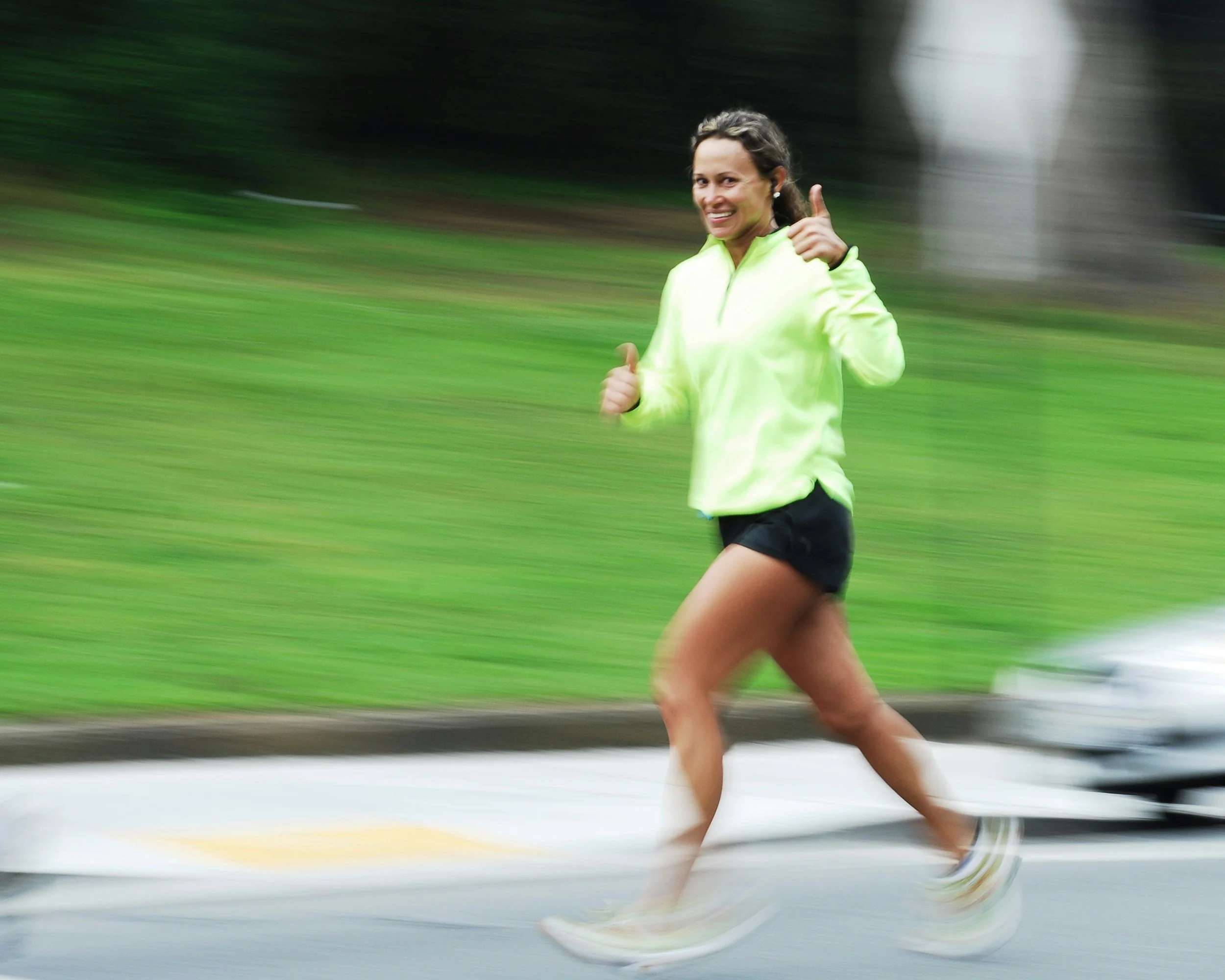 Middle aged woman running on a street and giving a thumbs up