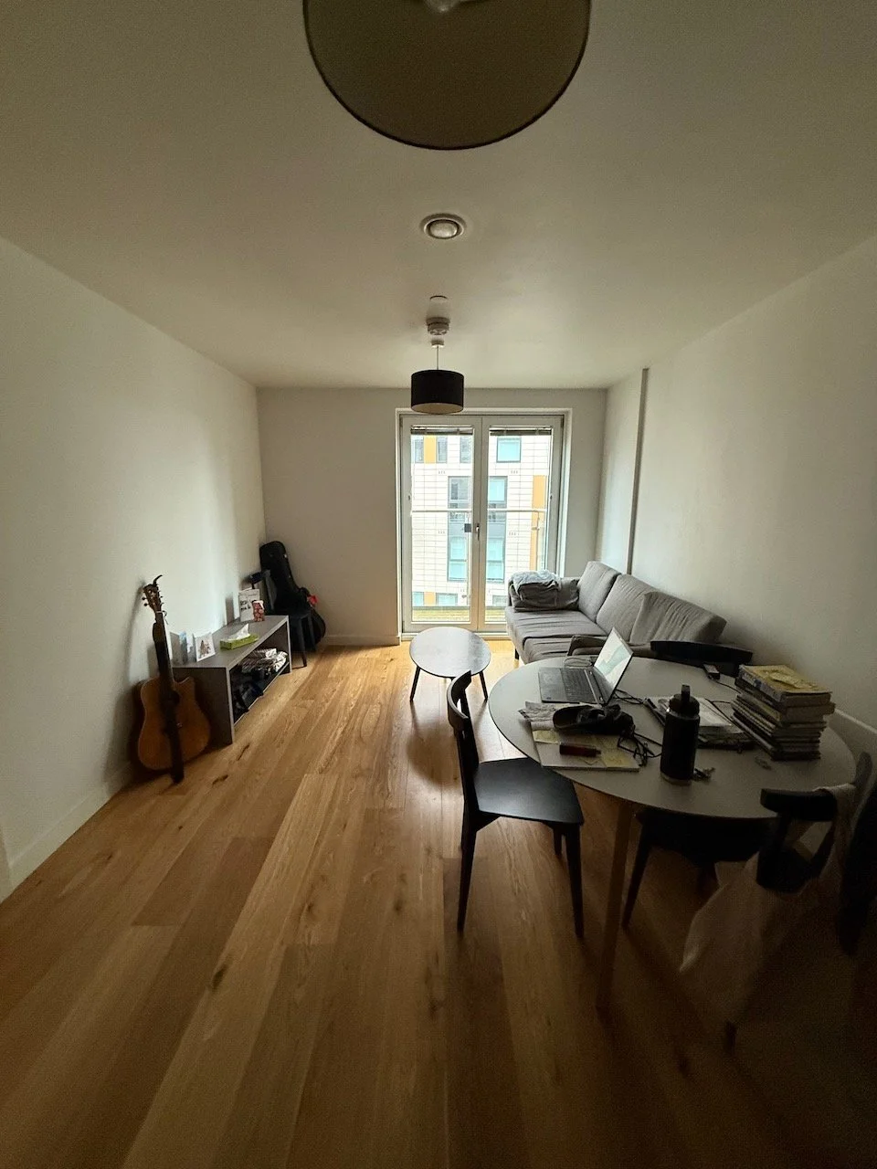 The furnished living room of Greg Corrigan’s new Manchester flat, with a guitar and a small number of personal belongings.