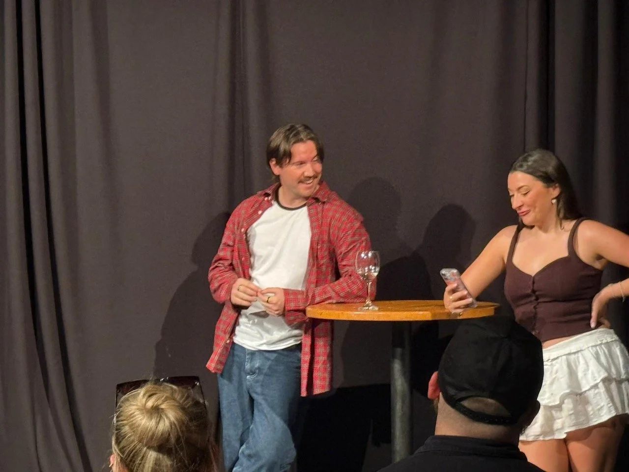 Greg Corrigan and another performer seated at a table during a Manchester acting showcase.