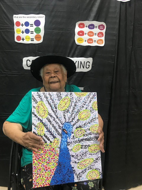 participant with hat holding her art