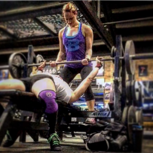 woman spotting another woman benching