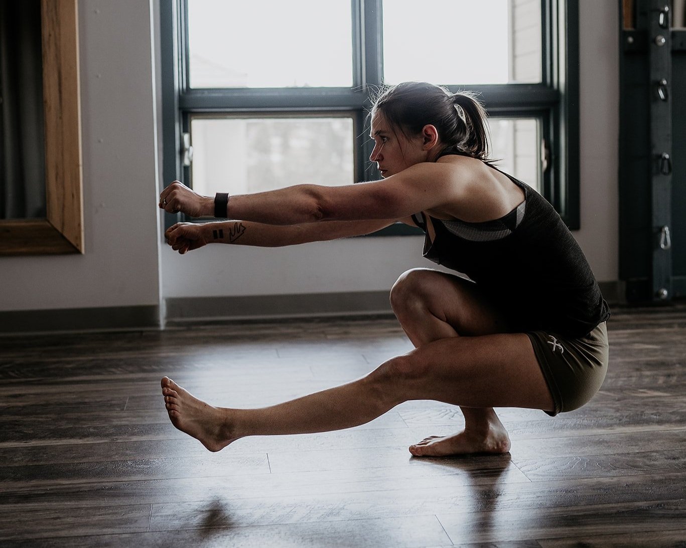 personal trainer performing a pistol squat in bare feet