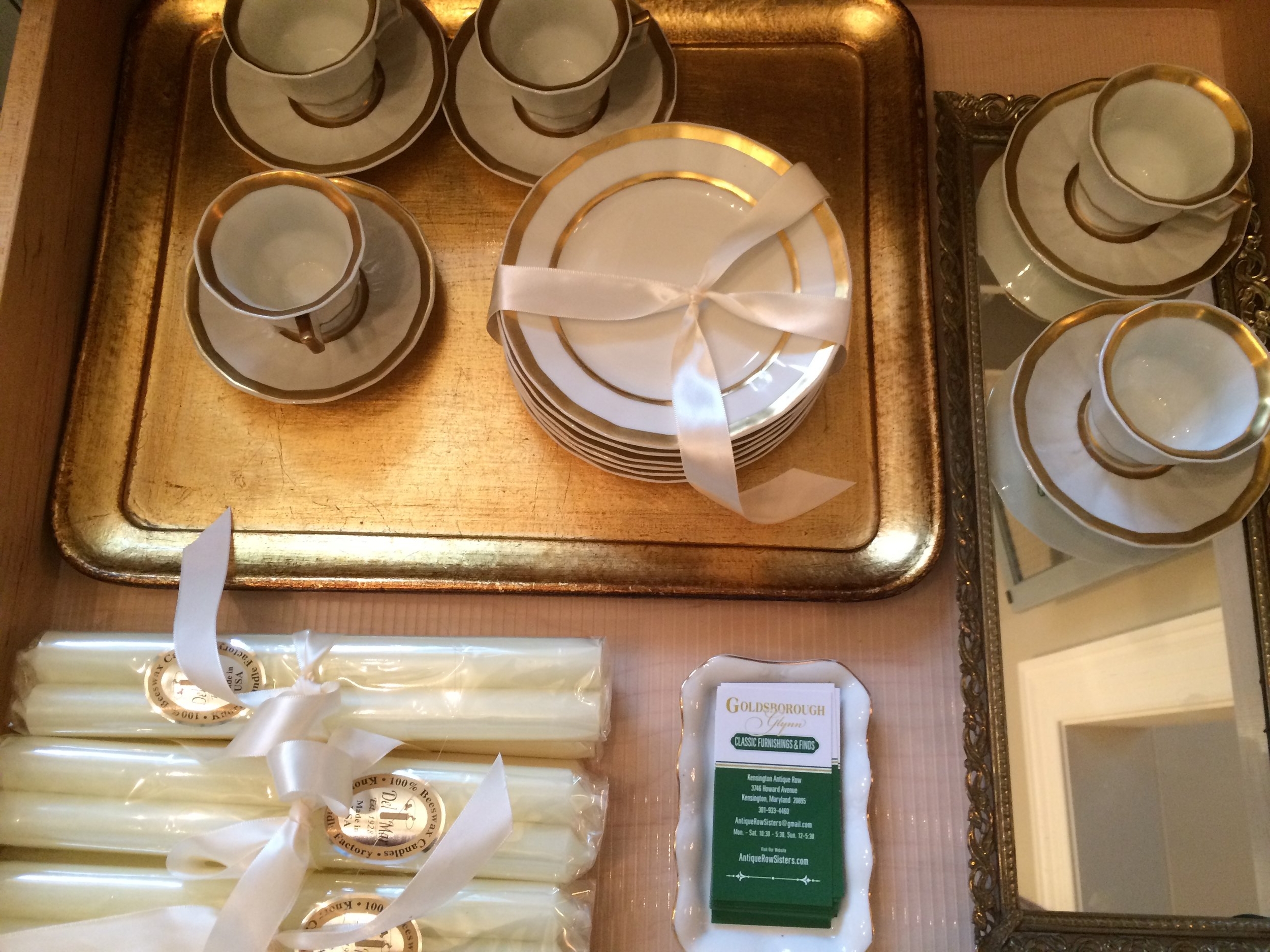 An ivory and gold drawer of limoge cups and saucers and Royal Cierge 100% bees wax candles sticks.