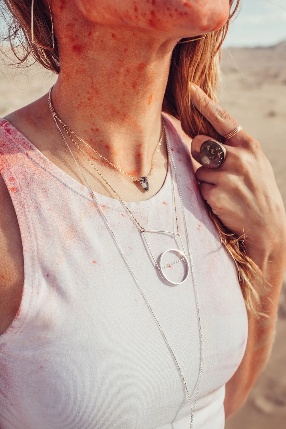 Detail of woman wearing geometric opal gemstone necklaces