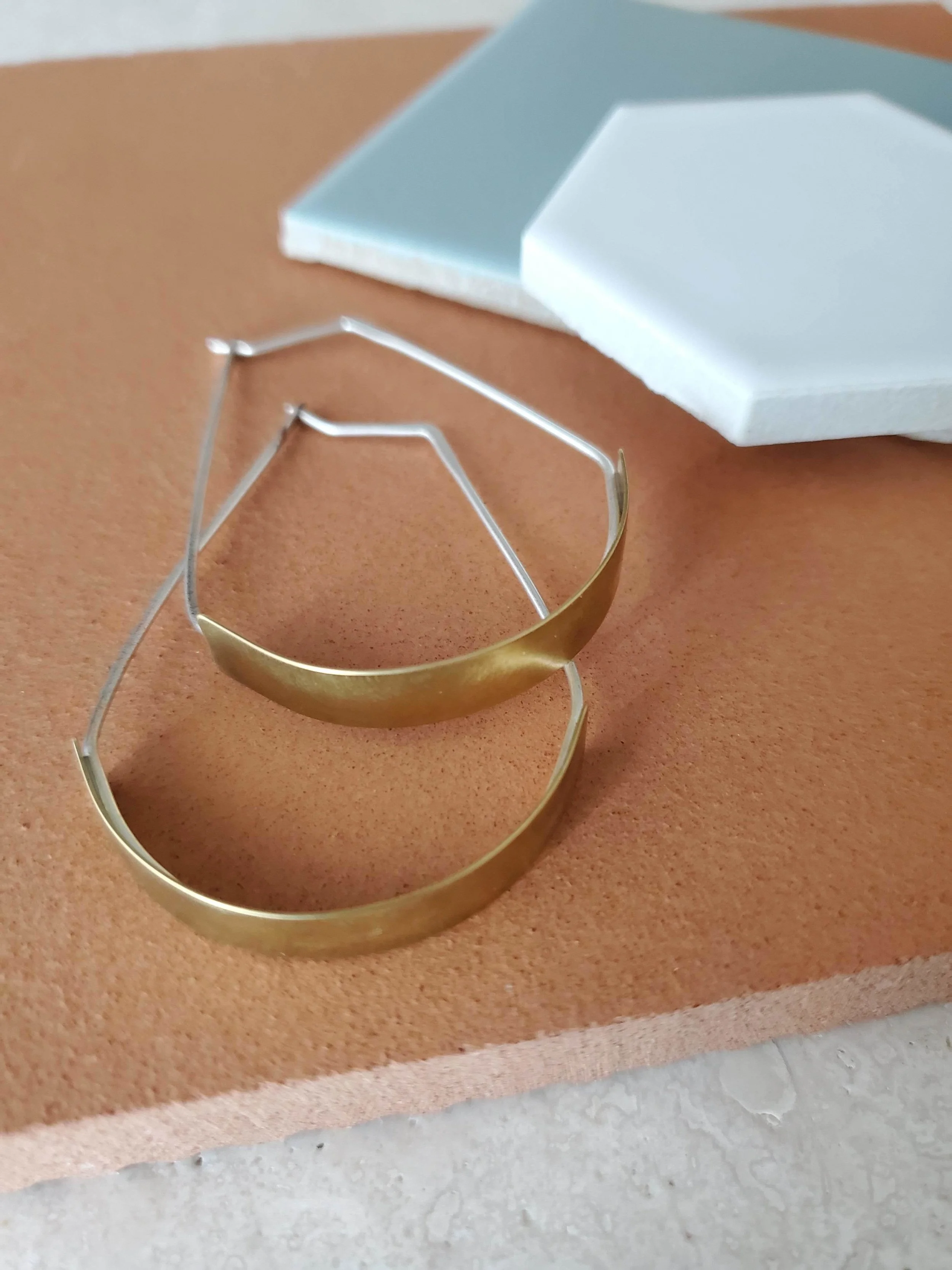 Side view of shiny hoop brass dangle earrings