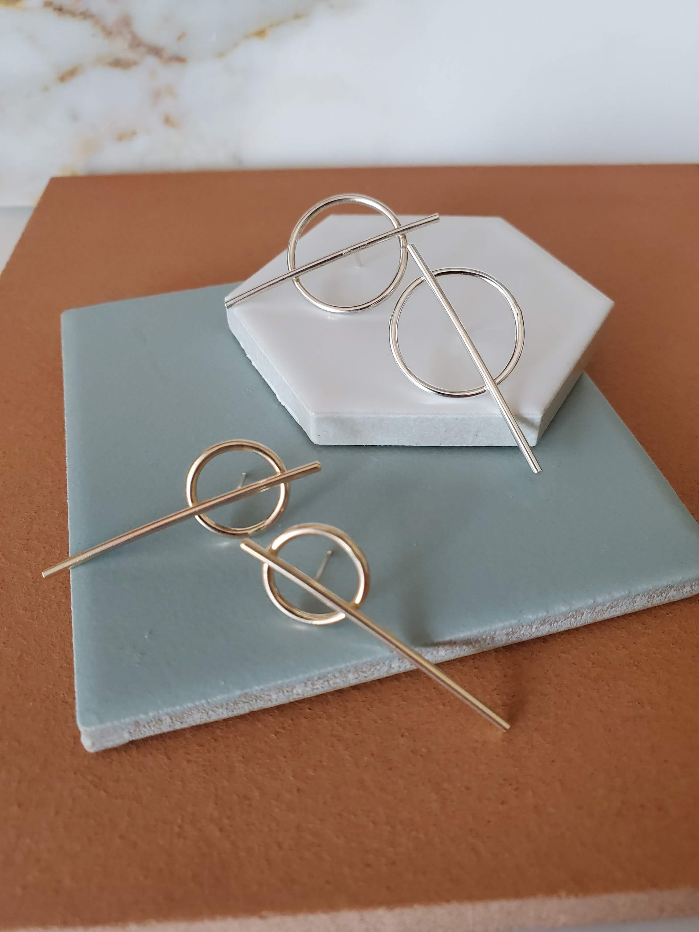 Silver and gold stud earrings with a line and circle