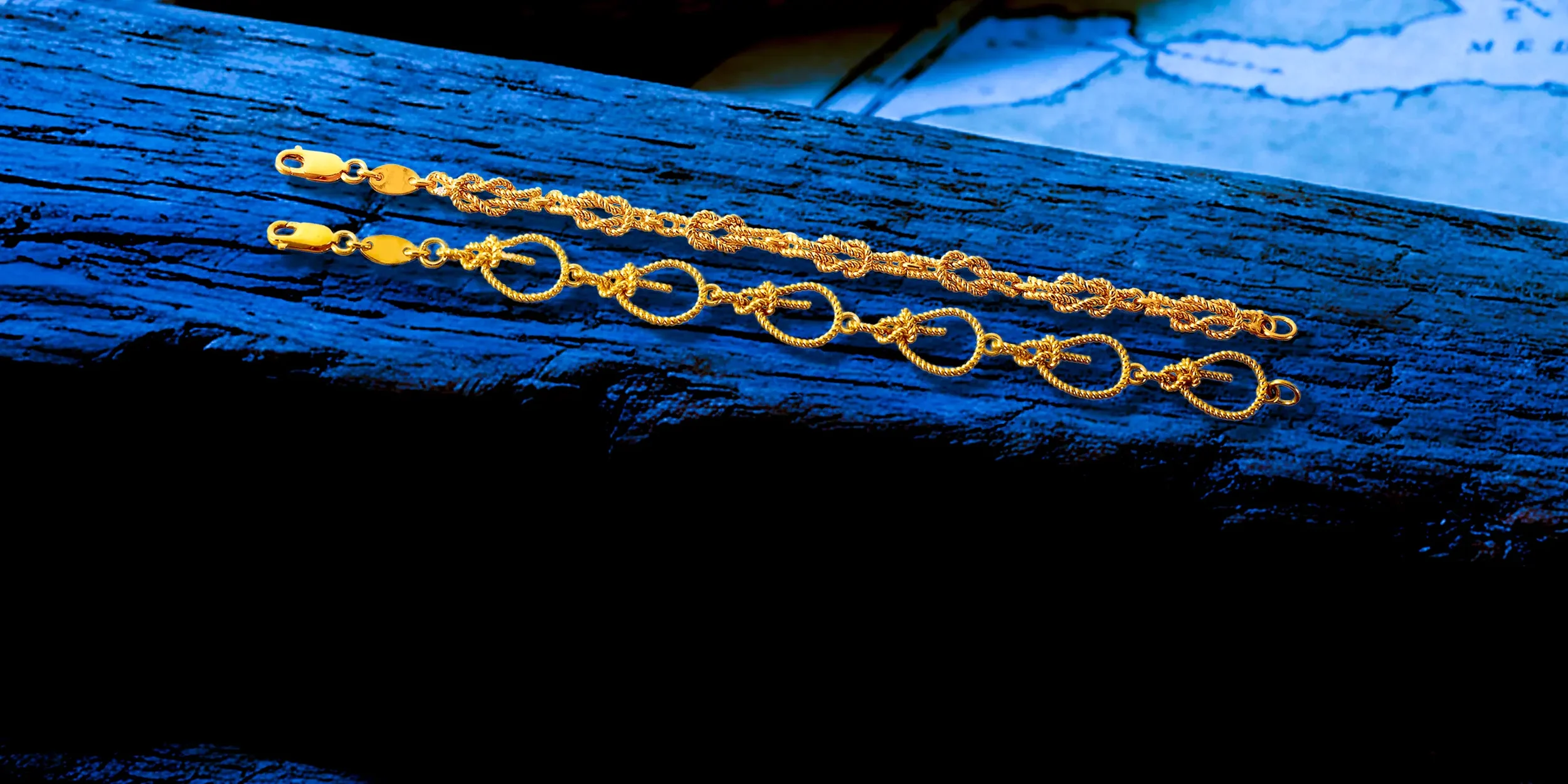 A gold bracelet with intricate knot and circle links resting on a textured dark blue wooden surface.