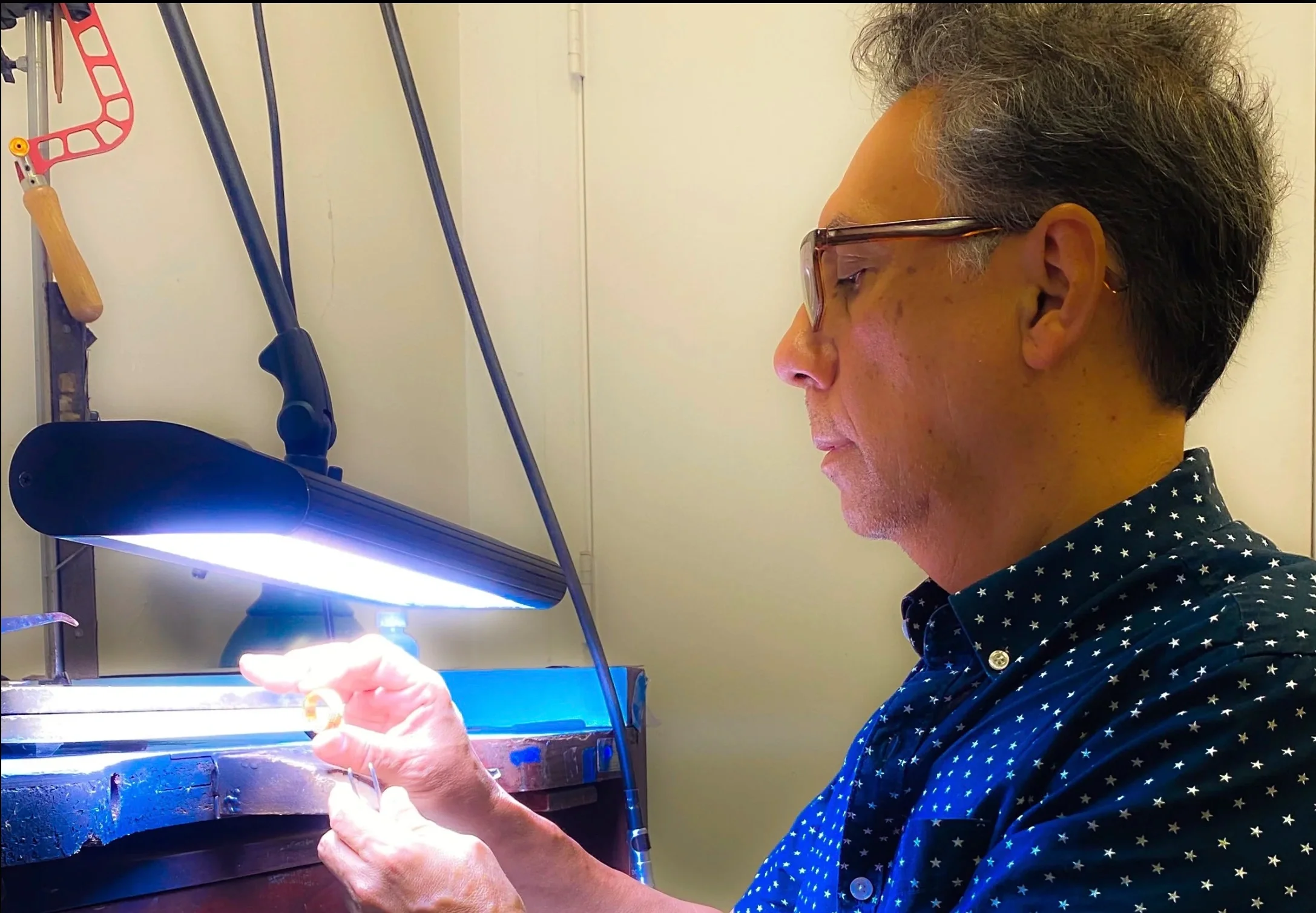 A master jeweler working on a ring with hand tools under a bright light