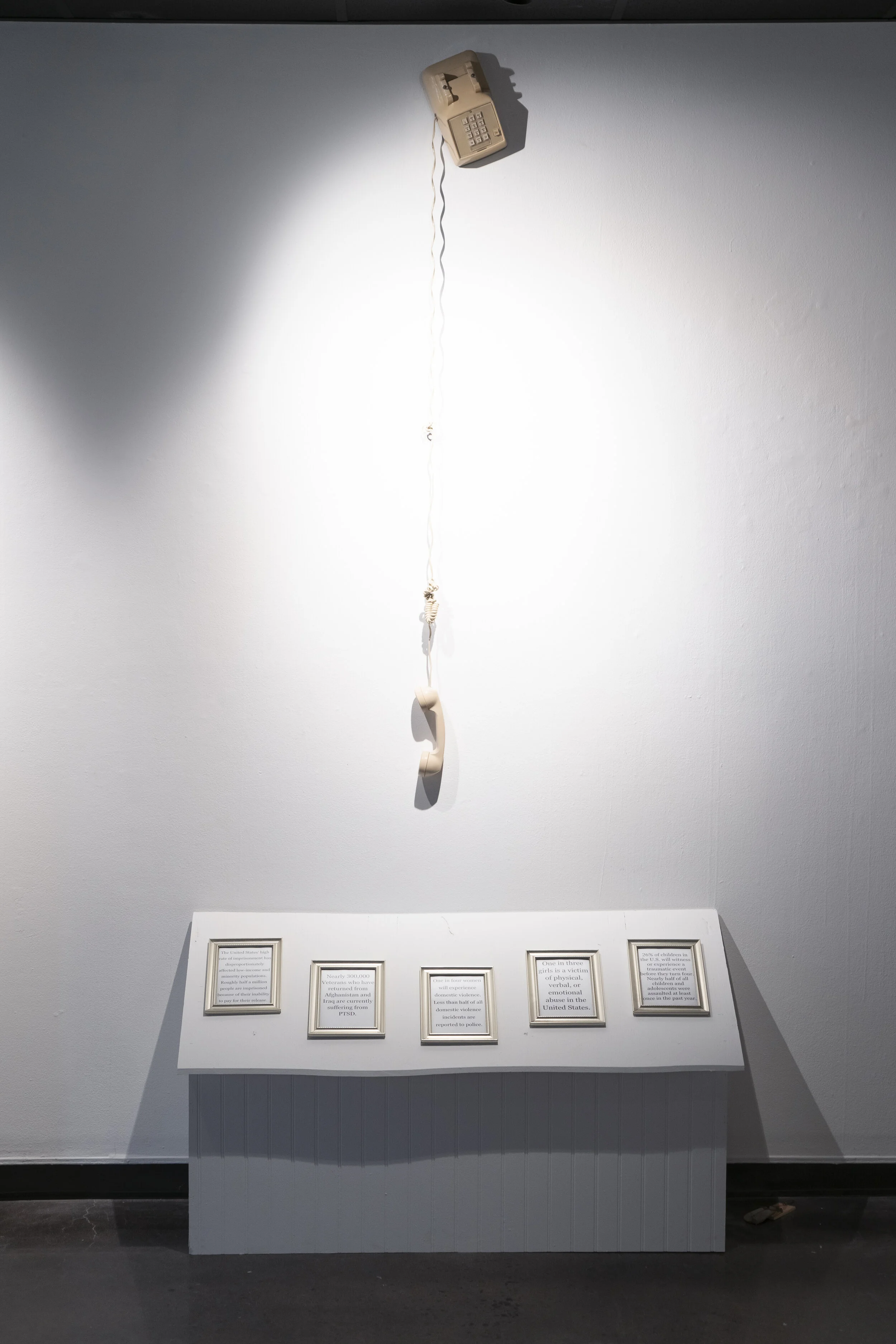 Dysfunction in the Household. 2021. Wood, frames, telephone, media components. Dysfunction in the Household is almost altar-like in its appearance. Within the five frames are five facts that coincide with the other five sculptures in the room. The bead-boarded house-like structure has a crisp but rough-cut exterior and holds all of the computer and noise components of the exhibition within. This piece has an auditory component that directly engages the audience. The sculpture creates an ambience for the exhibition/s entirety by playing a repetitive cricket chirping. This sound effect serves as a metaphor for the lack of discussion around these issues. By emphasizing the awkward silence,&nbsp;I hope that my artwork will spark more conversations surrounding trauma in our community.
