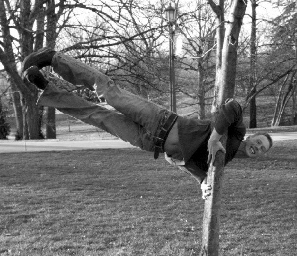 Brian demonstrating a flagpole on a tree, probably made easier due to his gymnastics background.