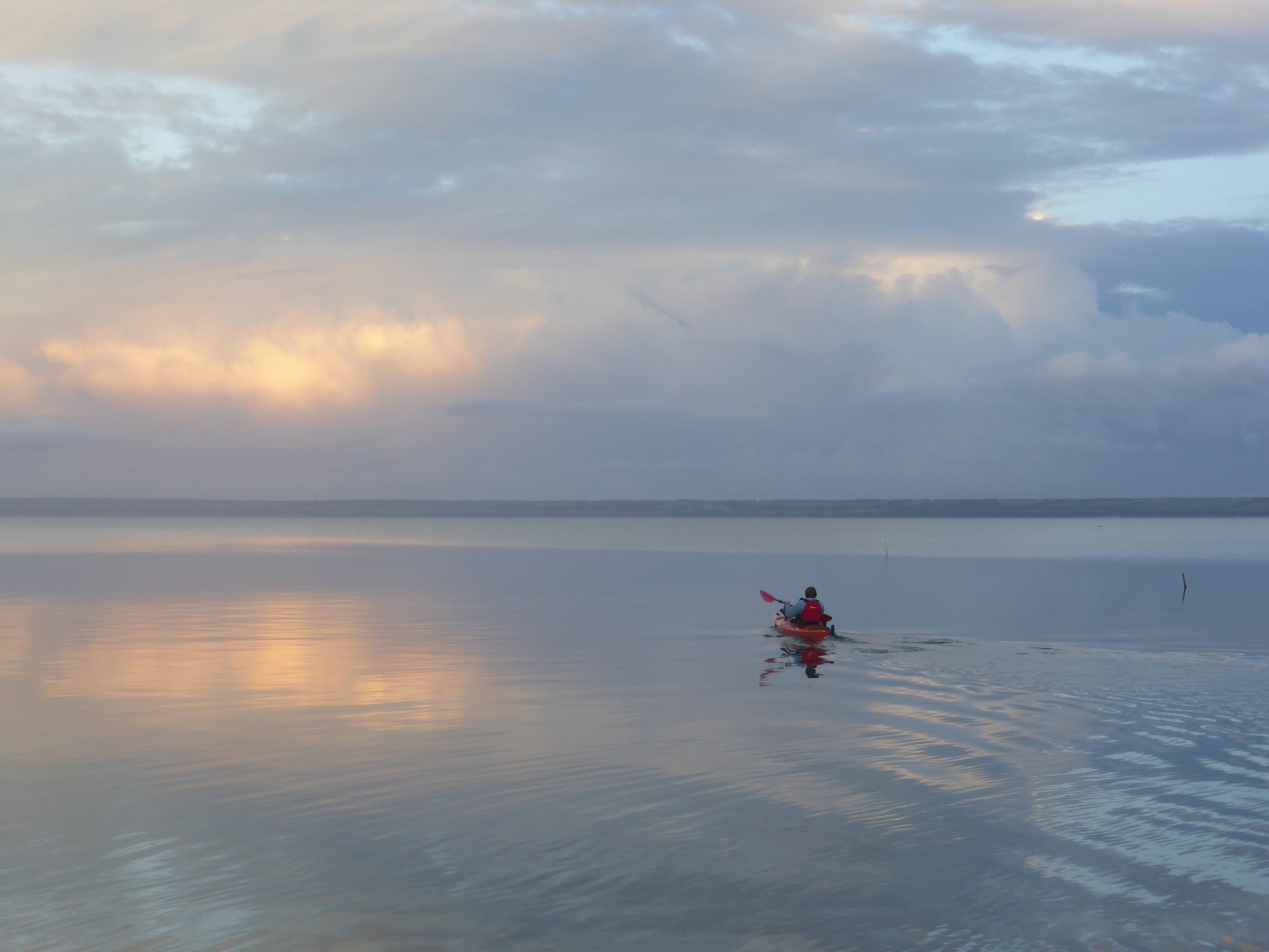 A kayak takes to the sea close to Island Chalet on a calm winter evening 