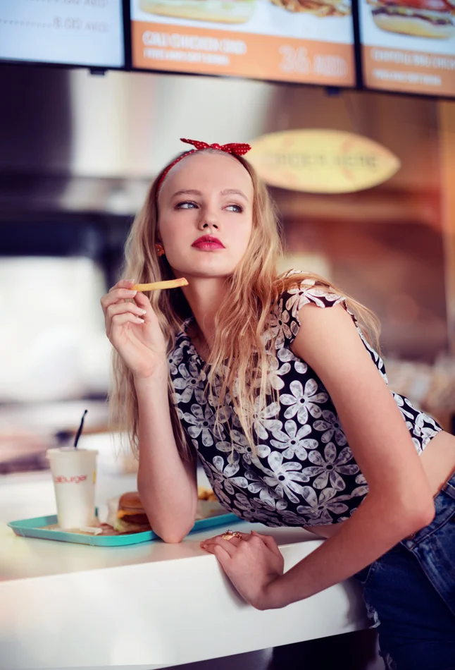 LA surf and skate Fashion editorial photoshoot. Model eating fries at a burger joint. Daniel Allison photography.