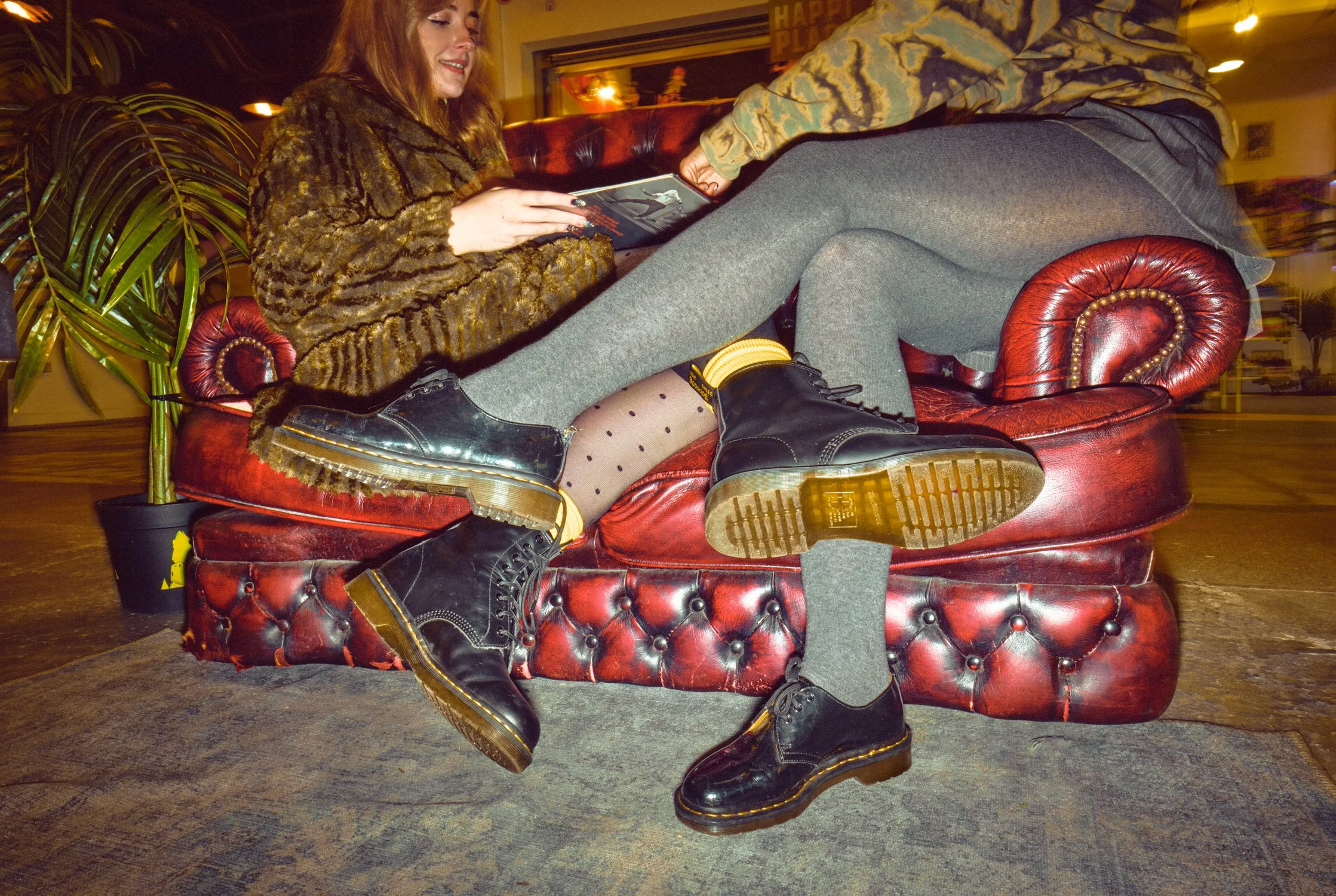 Dr. Martens street fashion campaign showing two women wearing black boots in a record shop, photographed by Daniel Allison.
