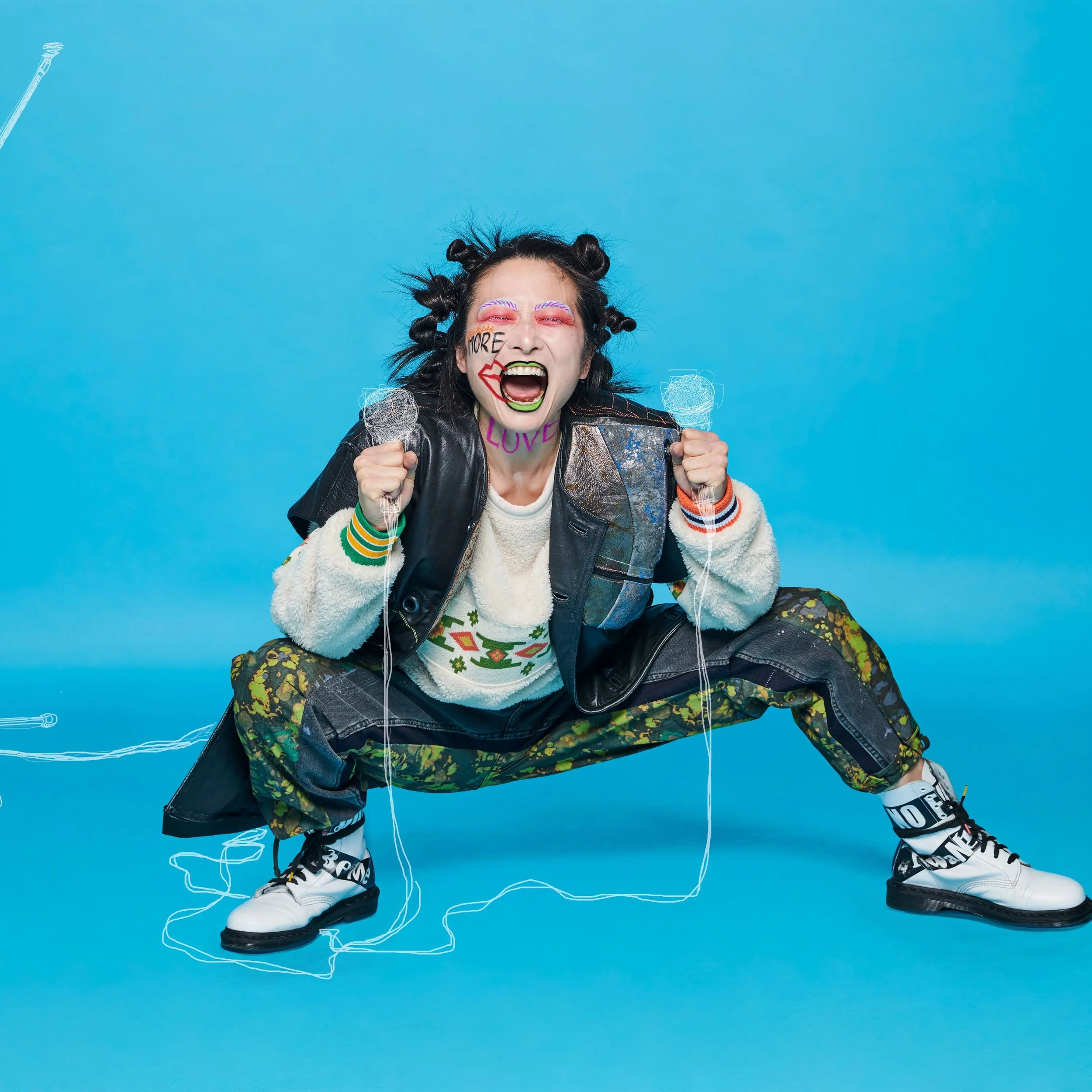 Model wearing Supramorphous upcycled fashion, featuring a reconstructed leather patchwork vest and repurposed denim pants, styled against a bright blue background