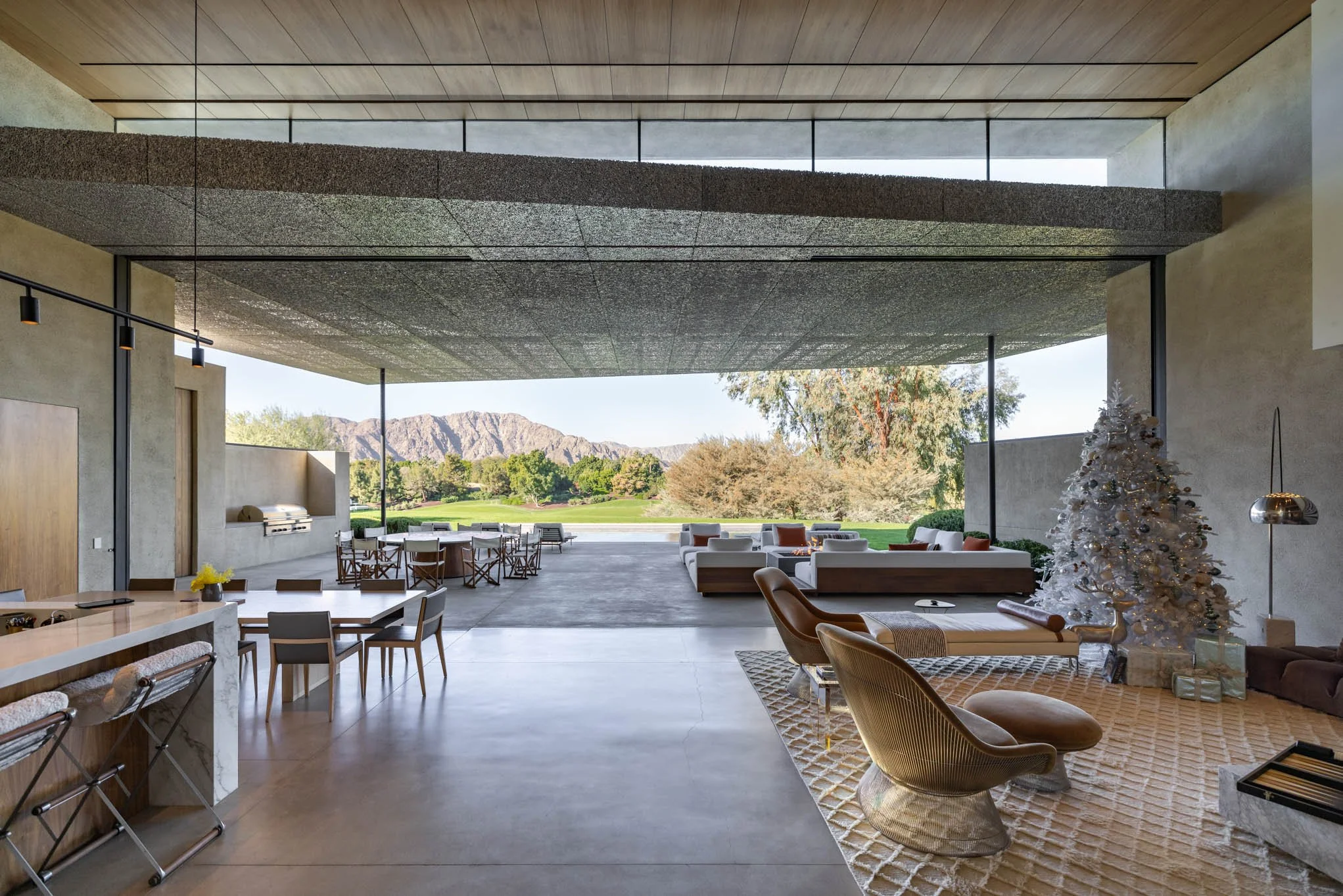 Modern open-concept living space with large sliding doors opening to an outdoor area with trees and mountains in the background