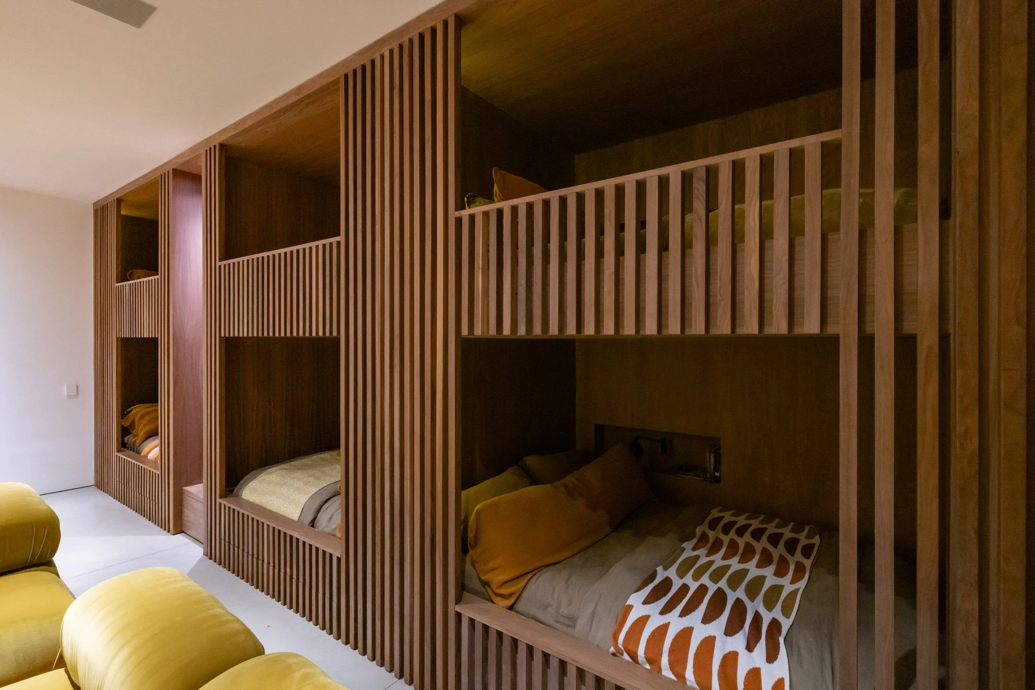 Wooden bunk beds with multiple sleeping compartments and colorful pillows in a modern room.