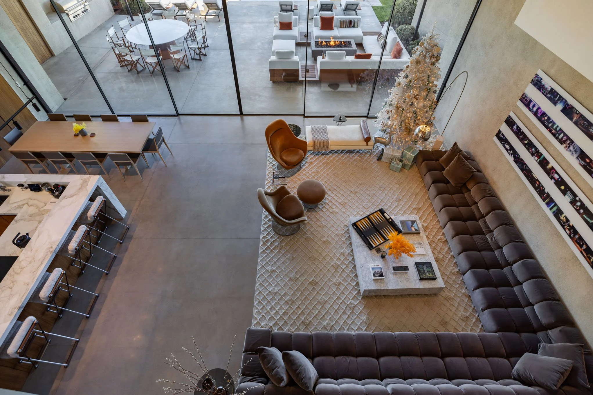 Modern living room with large sectional sofa, coffee table, and Christmas tree, adjacent to an outdoor patio with dining and seating areas.